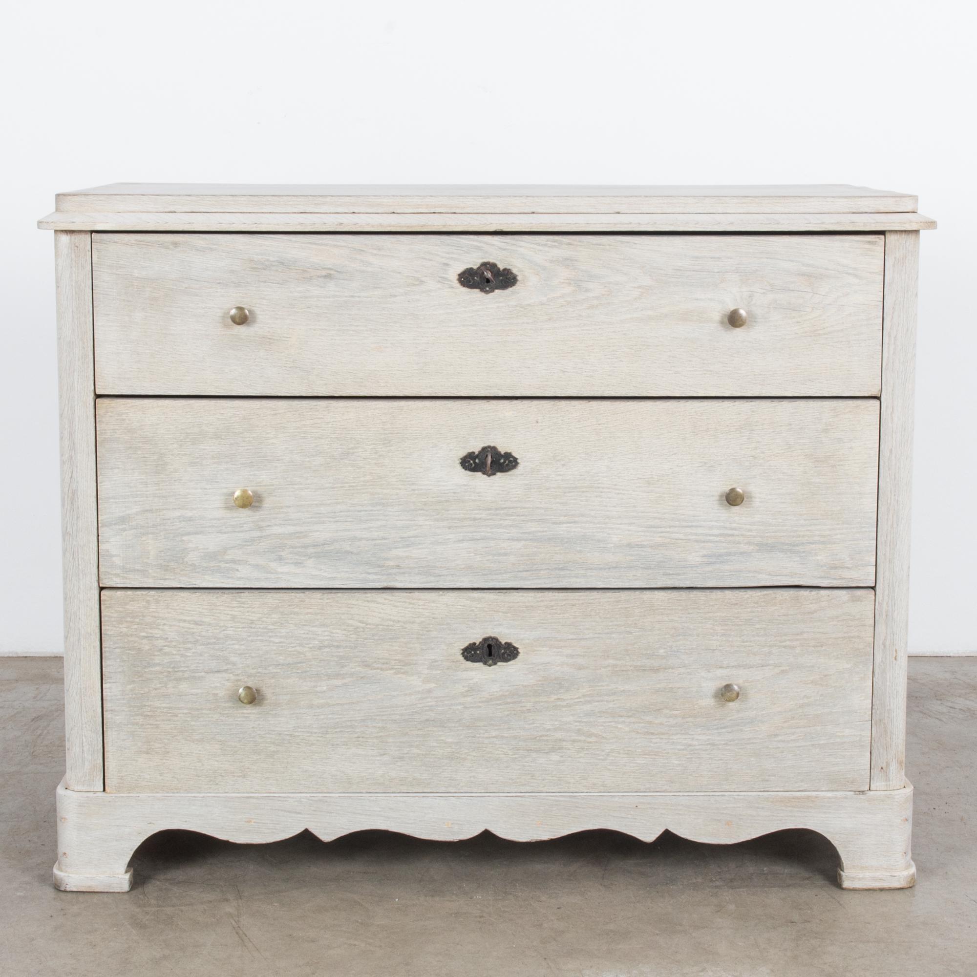 This bleached oak chest of drawers with a smooth finish was made in France, circa 1880. The drawers are slightly elevated, and the drawers feature decorative locks and circular pulls. The raised top and scalloped apron add style to this elegant