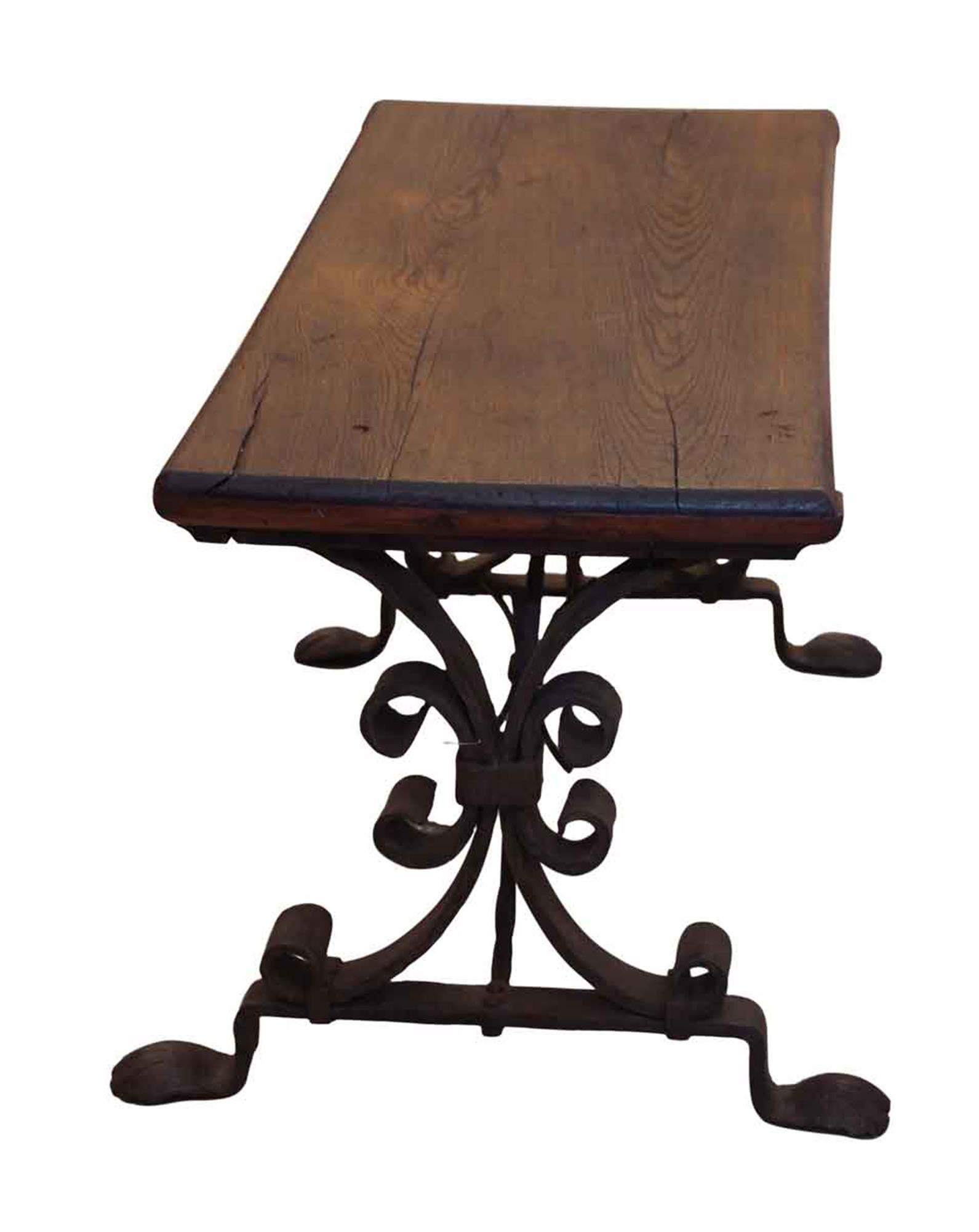 1880s dark wood tone bench with wrought iron and hand hammered legs. This can be seen at our 333 West 52nd St location in the Theater District West of Manhattan.