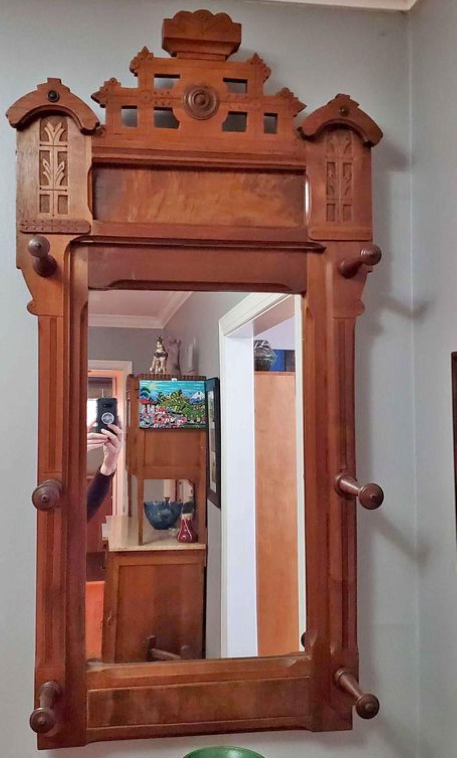 Beautiful 1880s Eastlake mirror. Hangs on wall and great for the entry hall. Six large pegs intended to hold your hats, which everyone wore back then! Dark walnut with burl inlay. Mesures: 48