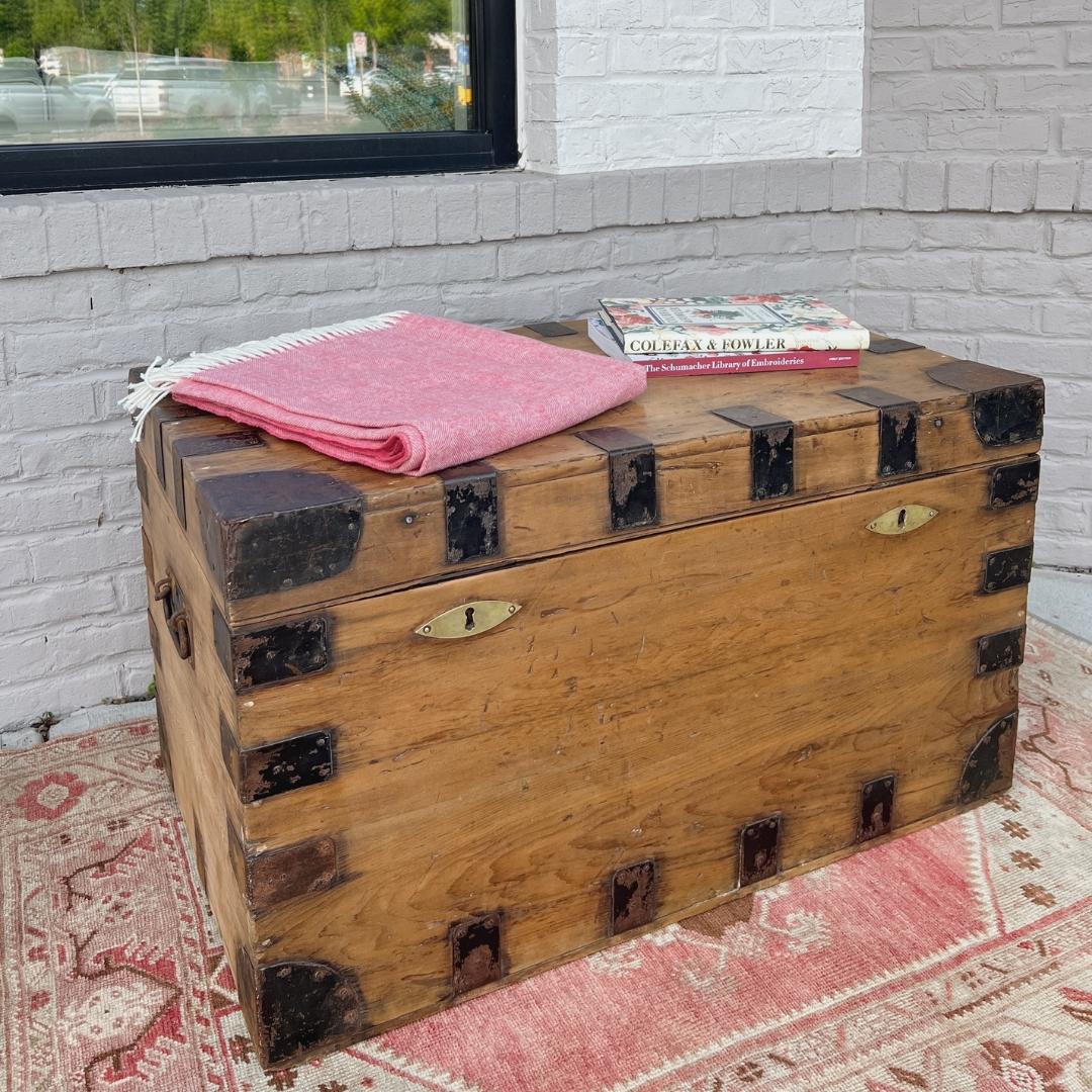 circa 1880s England. 
 
This Victorian pine chest would make a lovely coffee table, end of bed storage, or rustic toy box. The chest is iron bound along all sides, each corner is iron capped, and finished with iron carrying handles. The fine grain