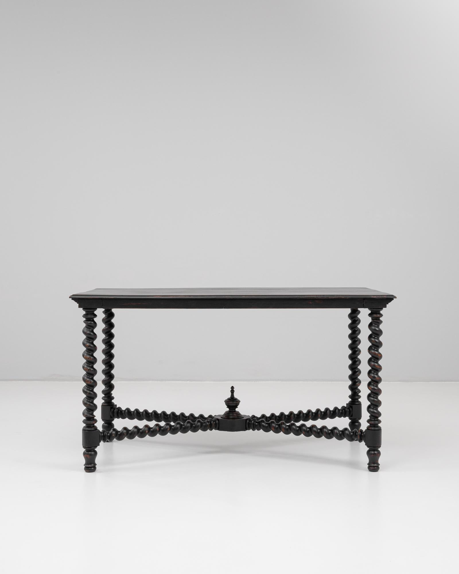 This 1880s French table features an elegant black patinated finish and striking barley twist legs, embodying the refined craftsmanship of the late 19th century. The rectangular top rests on four elaborately turned legs, connected by equally