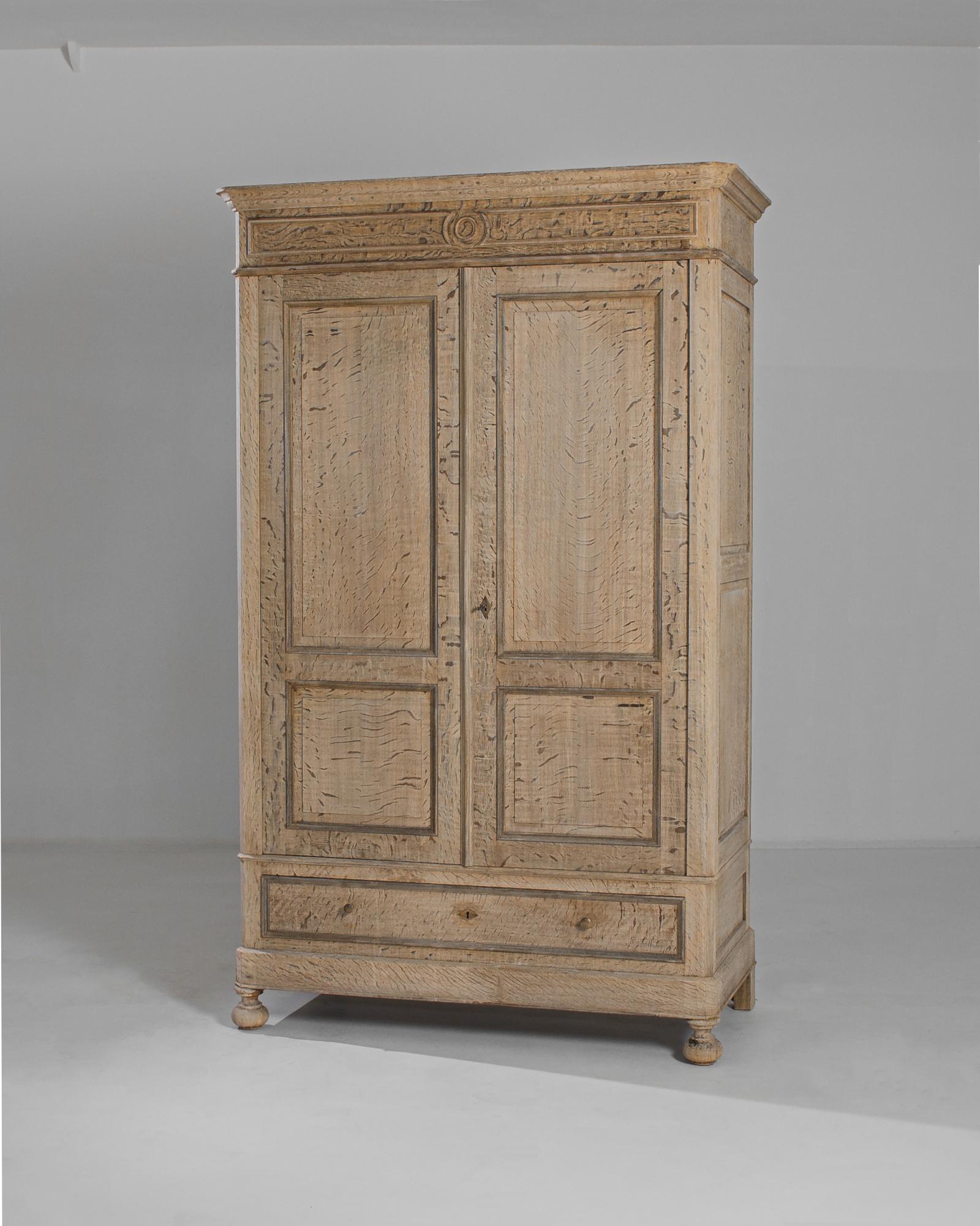 This bleached oak armoire with crown molding was made in France, circa 1880. Crafted by artisans in the past and meticulously refreshed in our atelier, the armoire displays a light finish evoking the charm of a rustic farmhouse. It features spacious