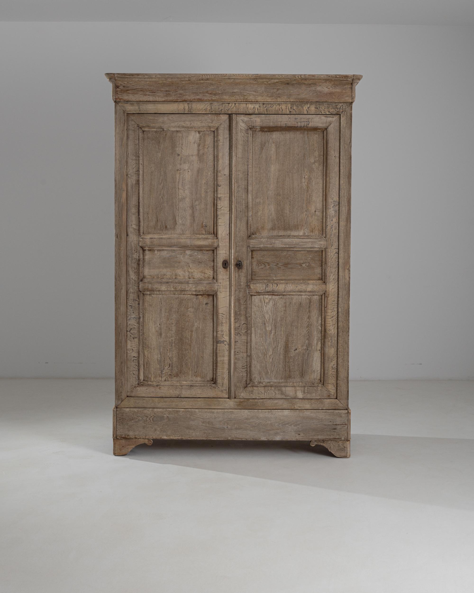 This tall wooden armoire was produced in France, circa 1880. A poised and spacious armoire standing on scrolled bracket feet, featuring a sober cornice top, a large bottom drawer and a three-shelf case. The wood has been carefully restored in our