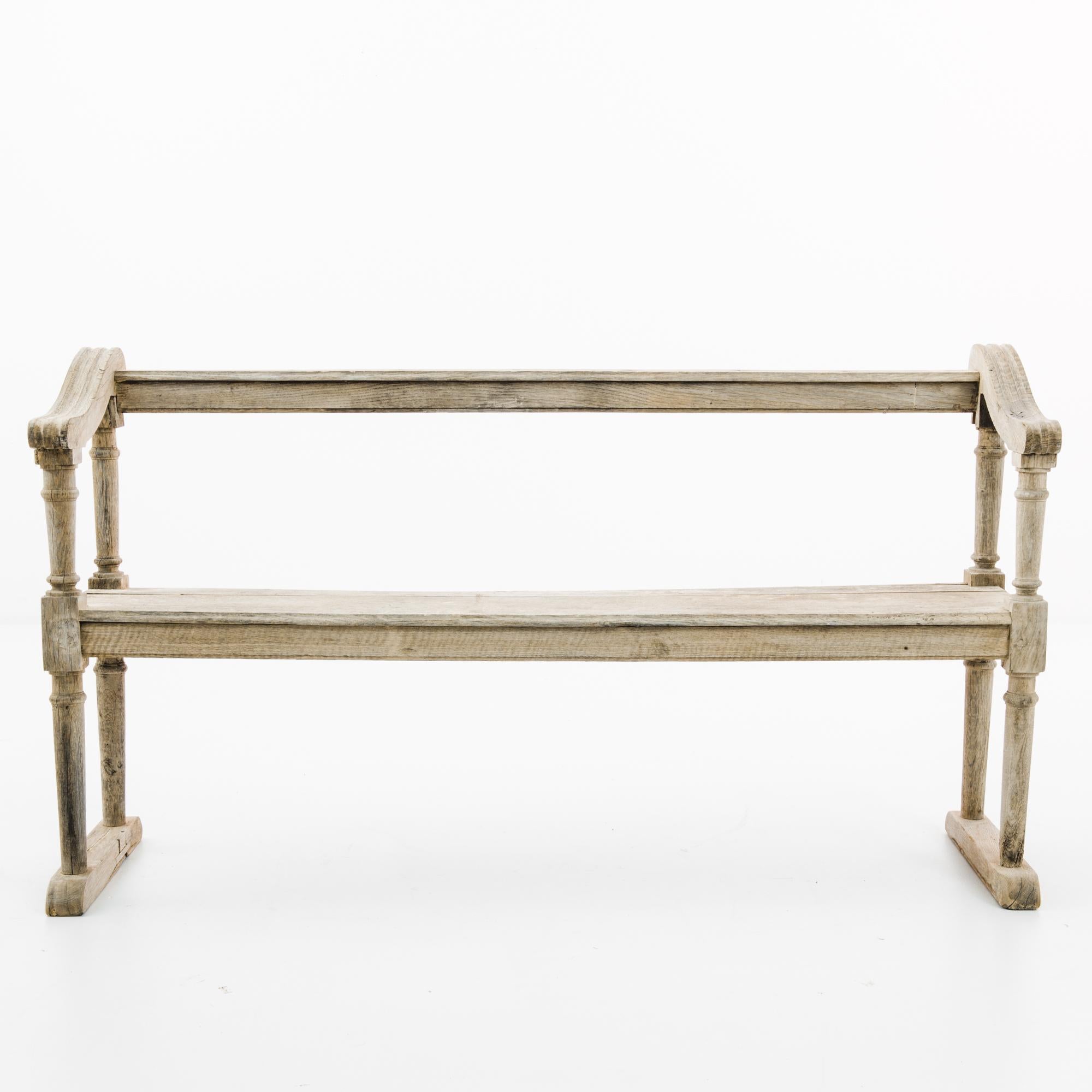 An oak bench from France, circa 1880. An upright pew-like frame, the sinuous slope of the armrests lends an graceful inflection. The wood has been restored to a natural finish, revealing the fine grain and subtle blush tones of the oak. The use of