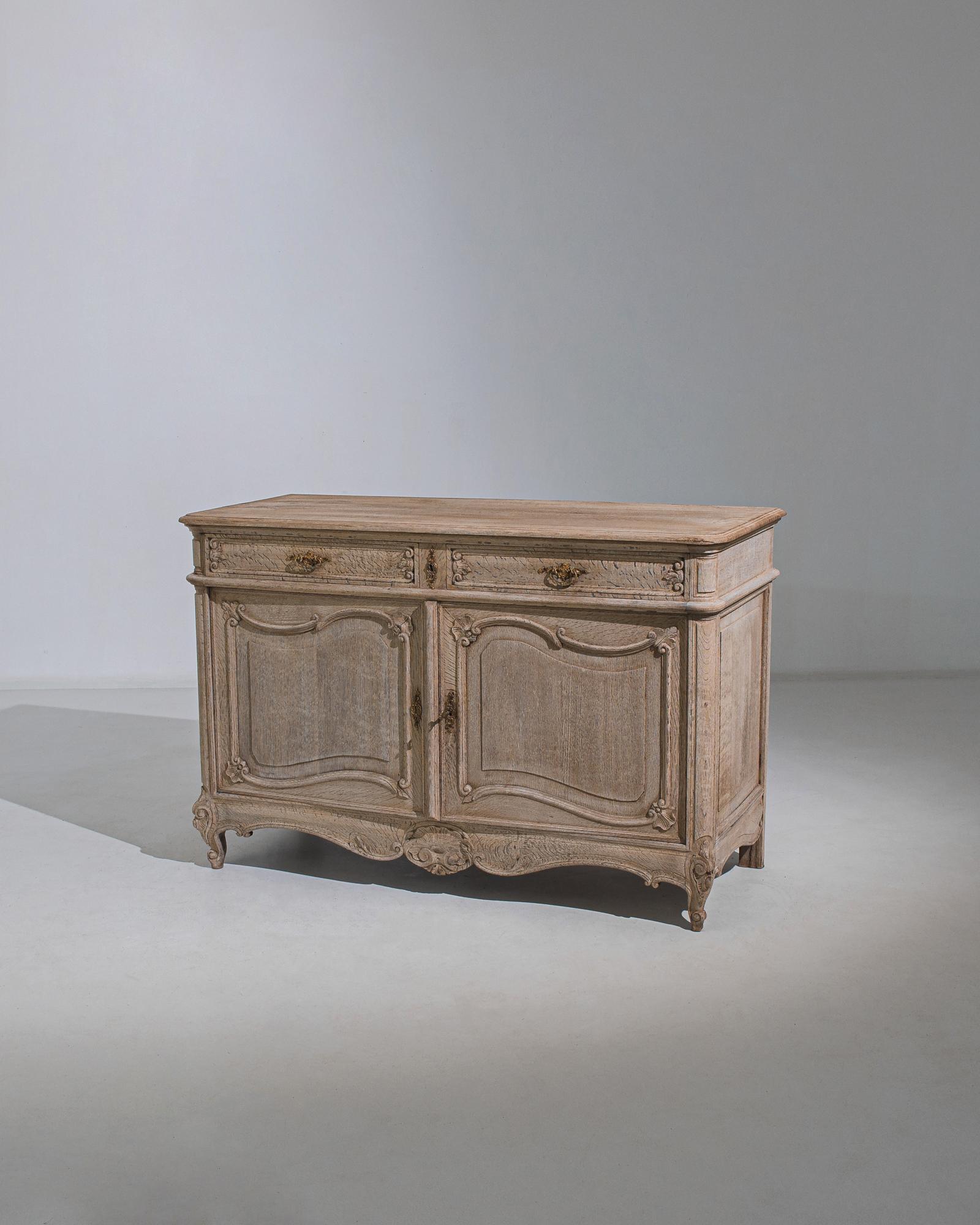 This bleached oak buffet was made in France, circa 1880. It displays smooth rounded edges and finely carved ornamentation marked by an alluring series of curves, from the scalloped apron to the sinuous paneling and volute feet. A pair of drawers is