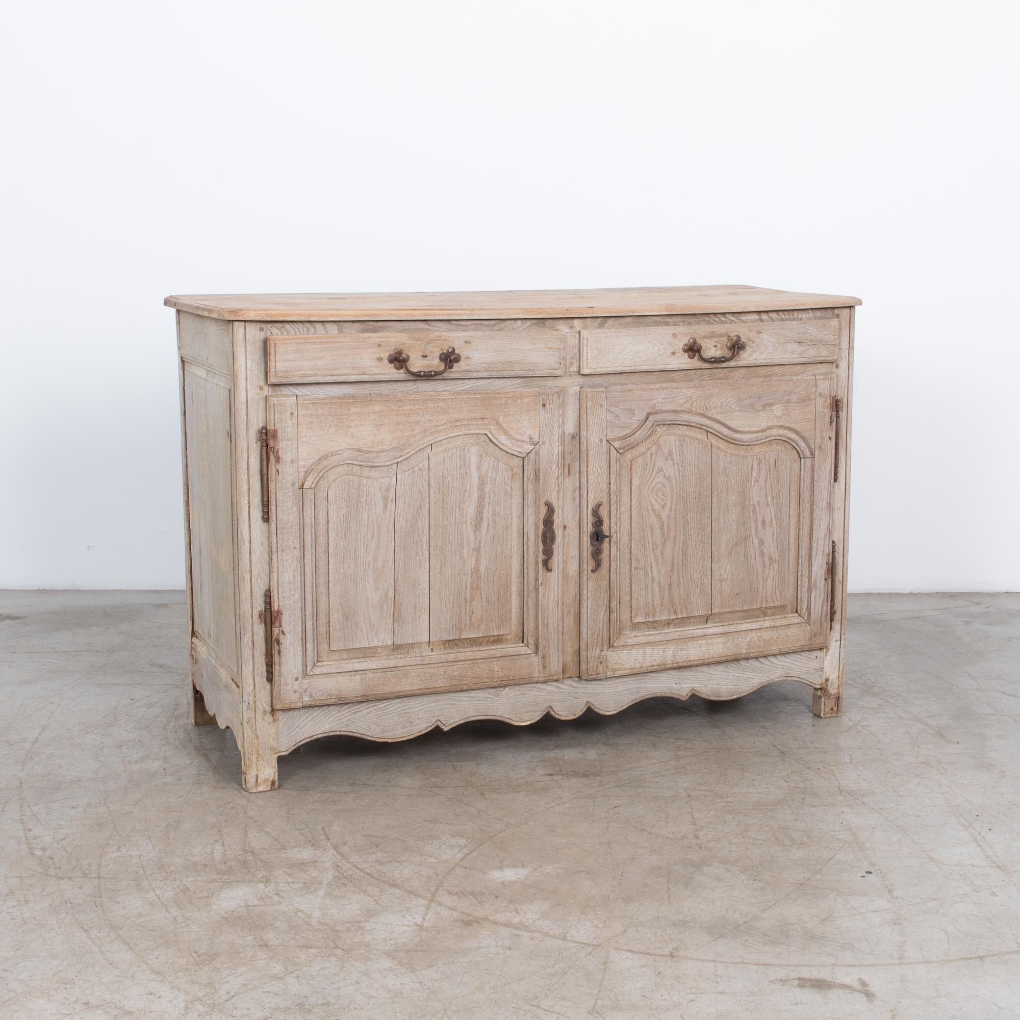 Experience the refined elegance of 1880s with the French Bleached Oak Buffet, a timeless piece that embodies the masterful craftsmanship of its era. The buffet is adorned with charming scalloped apron at the bottom, which adds to its graceful