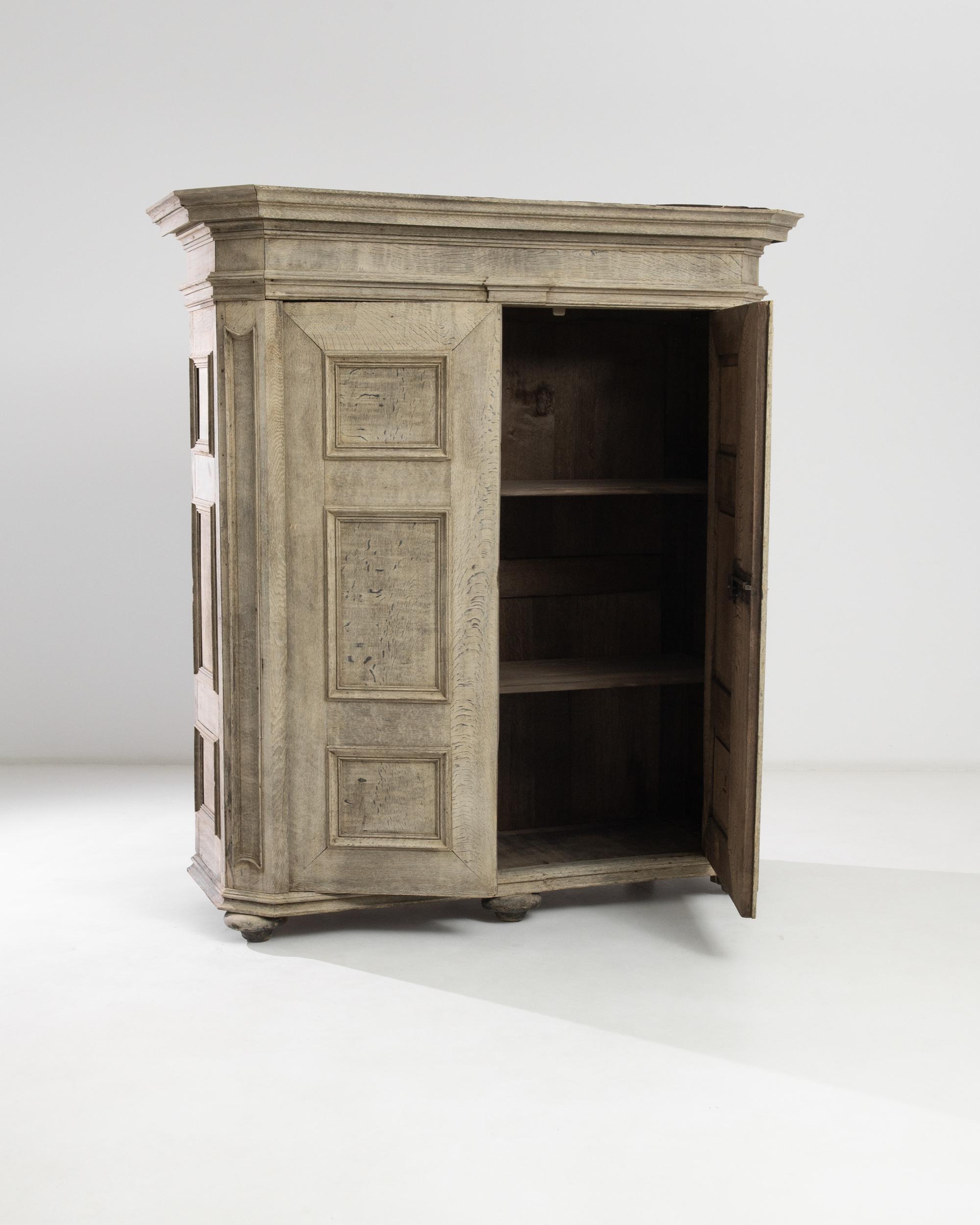 A bleached oak cabinet from France, produced circa 1880. Standing slightly over six feet, and spanning a width over five and a half feet, this august chest makes a statement: bold body branded by recessed boxes on flanks and facade. Features locking
