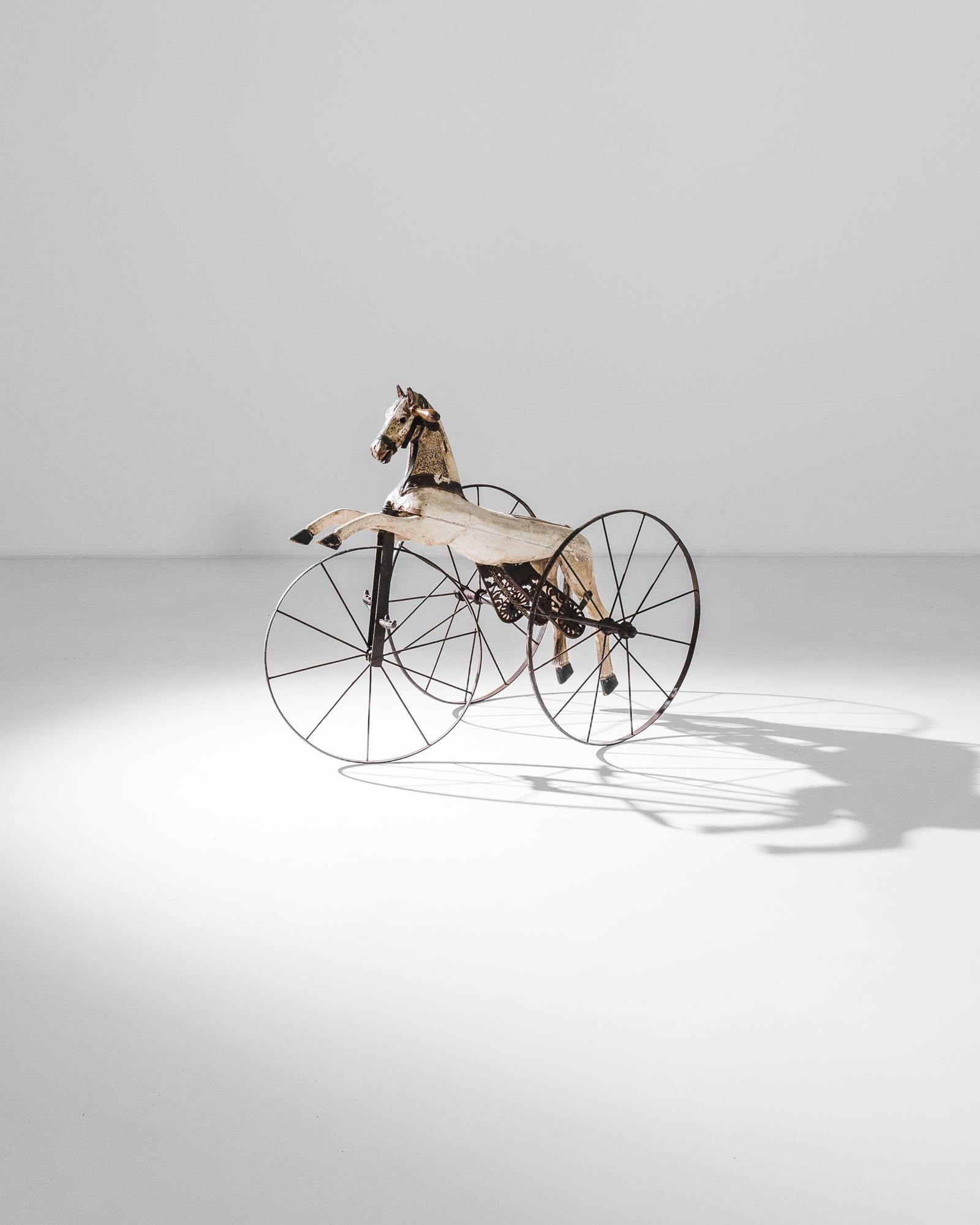 A horse tricycle from France, produced circa 1880. An antique children’s toy in the form of a leaping white horse with black bridle on three iron wheels. A charmingly simple mechanism built to ignite the imagination, to call on images of cowboys