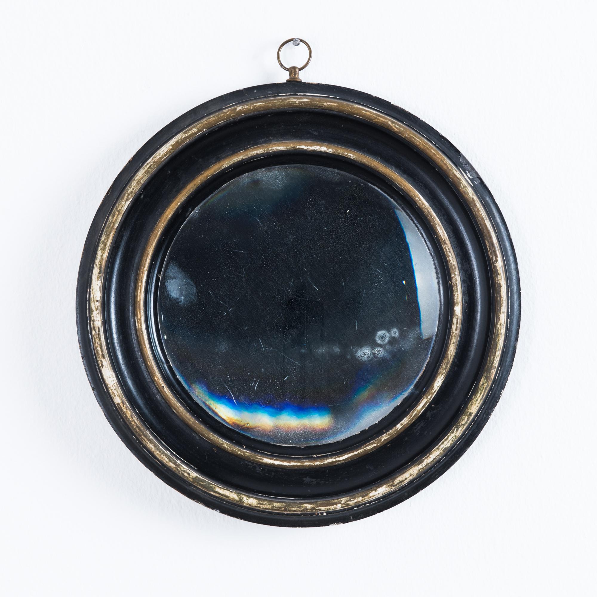 This circular mirror was made in France, circa 1880. Its wooden frame is painted black with two circles of aging gold leaf, circling the original mercury mirror. Mounting this mirror on the wall is effortless with the ring hook at the top.