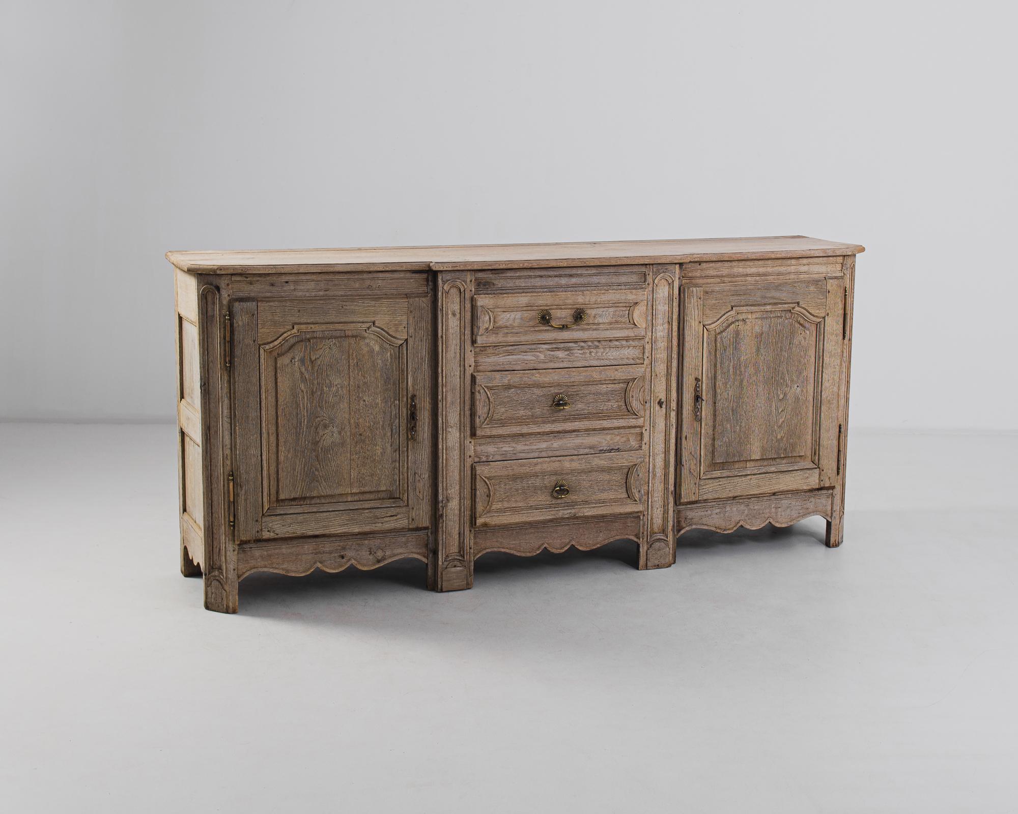 An oak buffet from 1880s France. The long, rectangular cabinet is enlivened by the contours of the paneling of the cupboards and drawers, and a scalloped apron. The wood has been restored in our workshops to an organic finish, revealing the natural