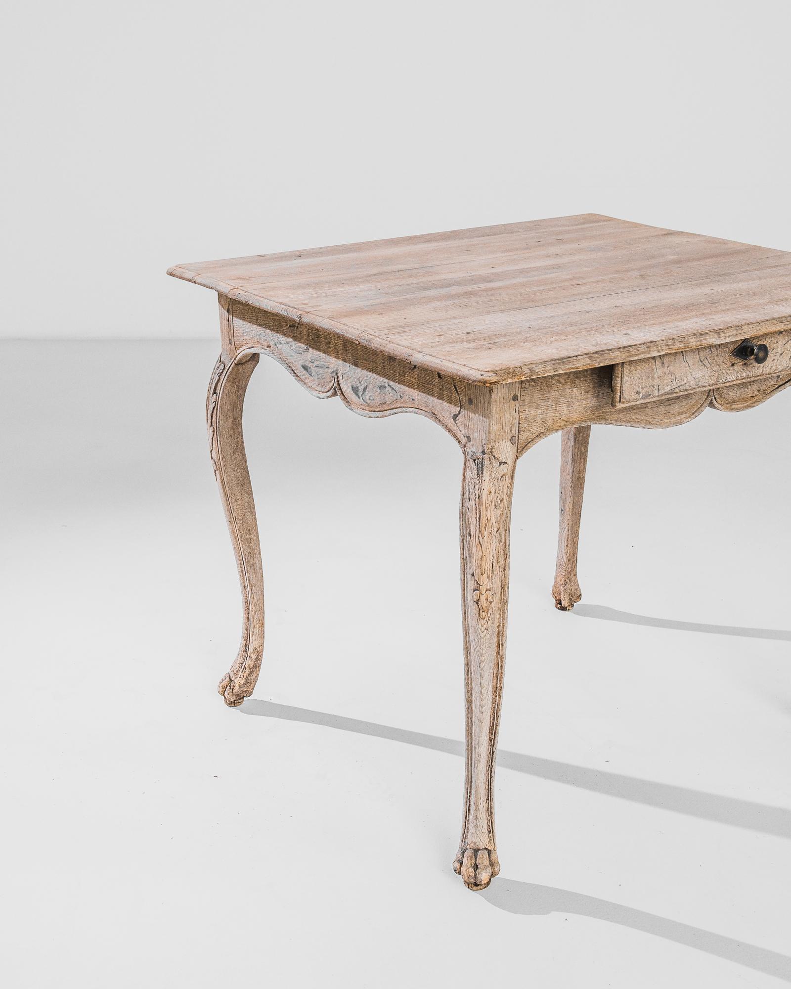 Cabriole legs, ending in carved claw feet, give this oak occasional table an elegant stance. Made in France in the 1880s, the wood has been restored to an organic finish, revealing the soft russet tone of the natural oak. A scalloped apron houses a