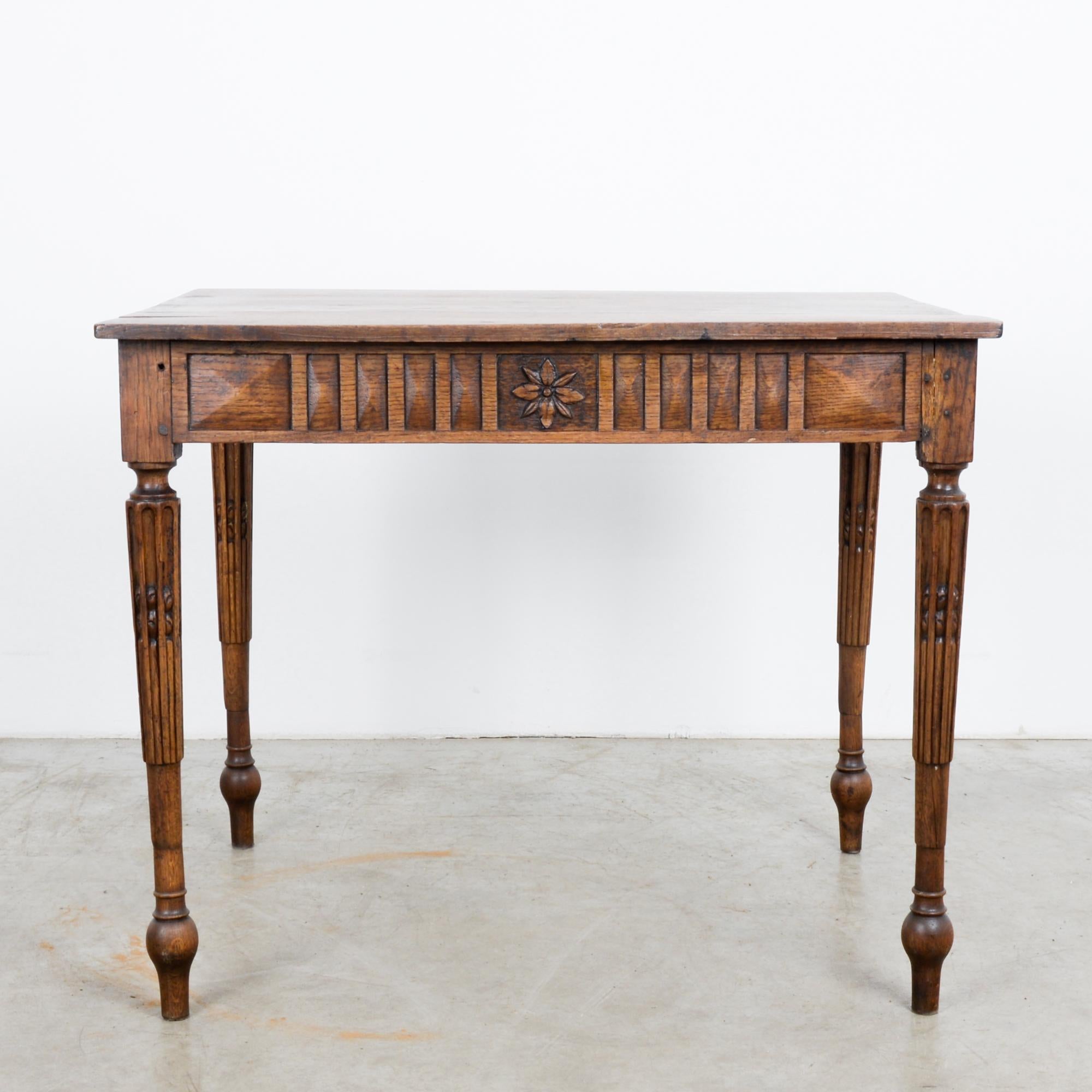 This wooden side table was made in France, circa 1880. It features a carved apron with rosettes in the center and neoclassical elements with fluted legs. The tabletop consists of wooden planks, which have a beautiful, time-worn patina. The deep and