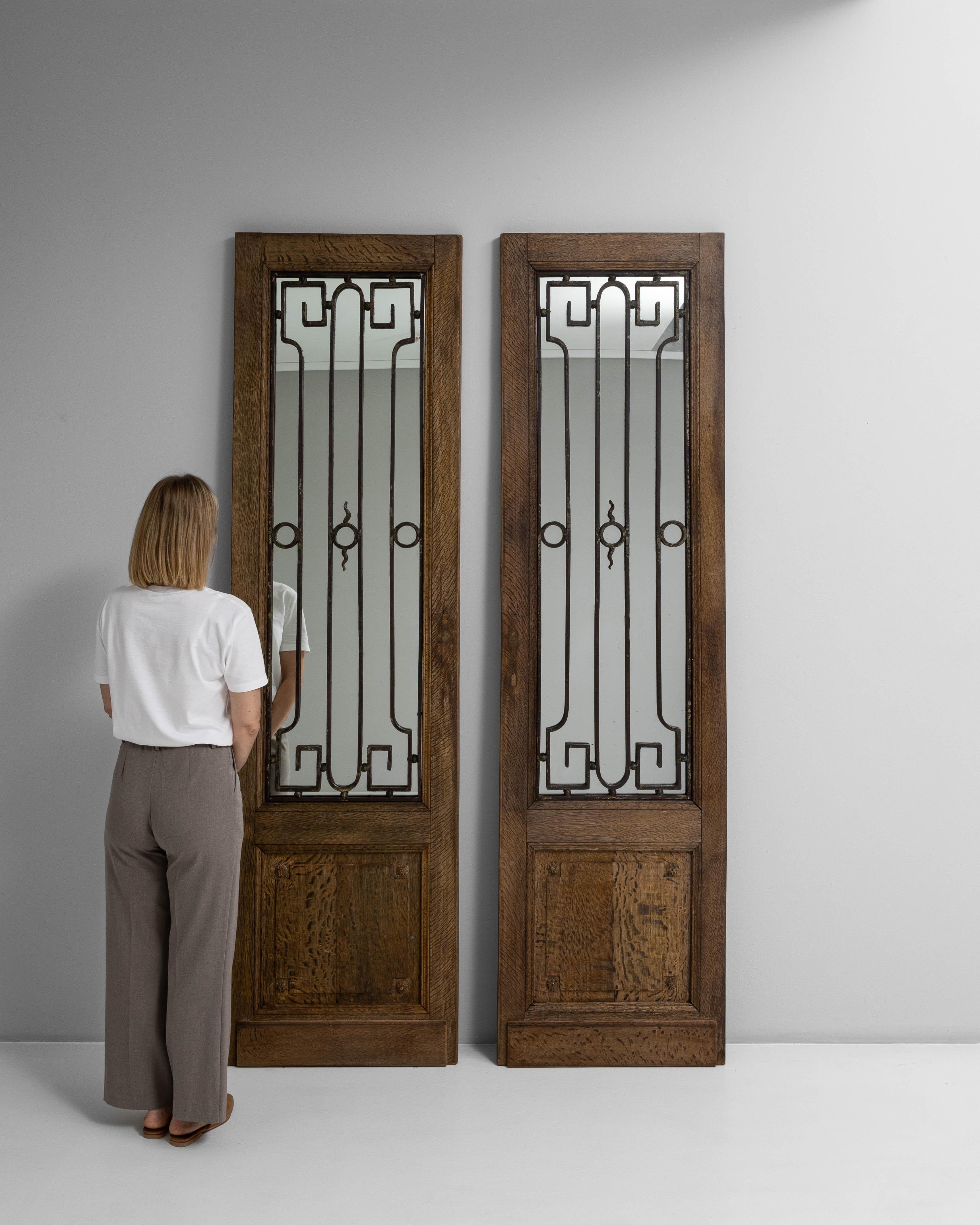 Questa elegante coppia di porte-finestre del 1880 mette in mostra una raffinata miscela di artigianato e design senza tempo. Ogni porta presenta un pannello a specchio incorniciato da intricati dettagli in ferro battuto, che aggiungono profondità e