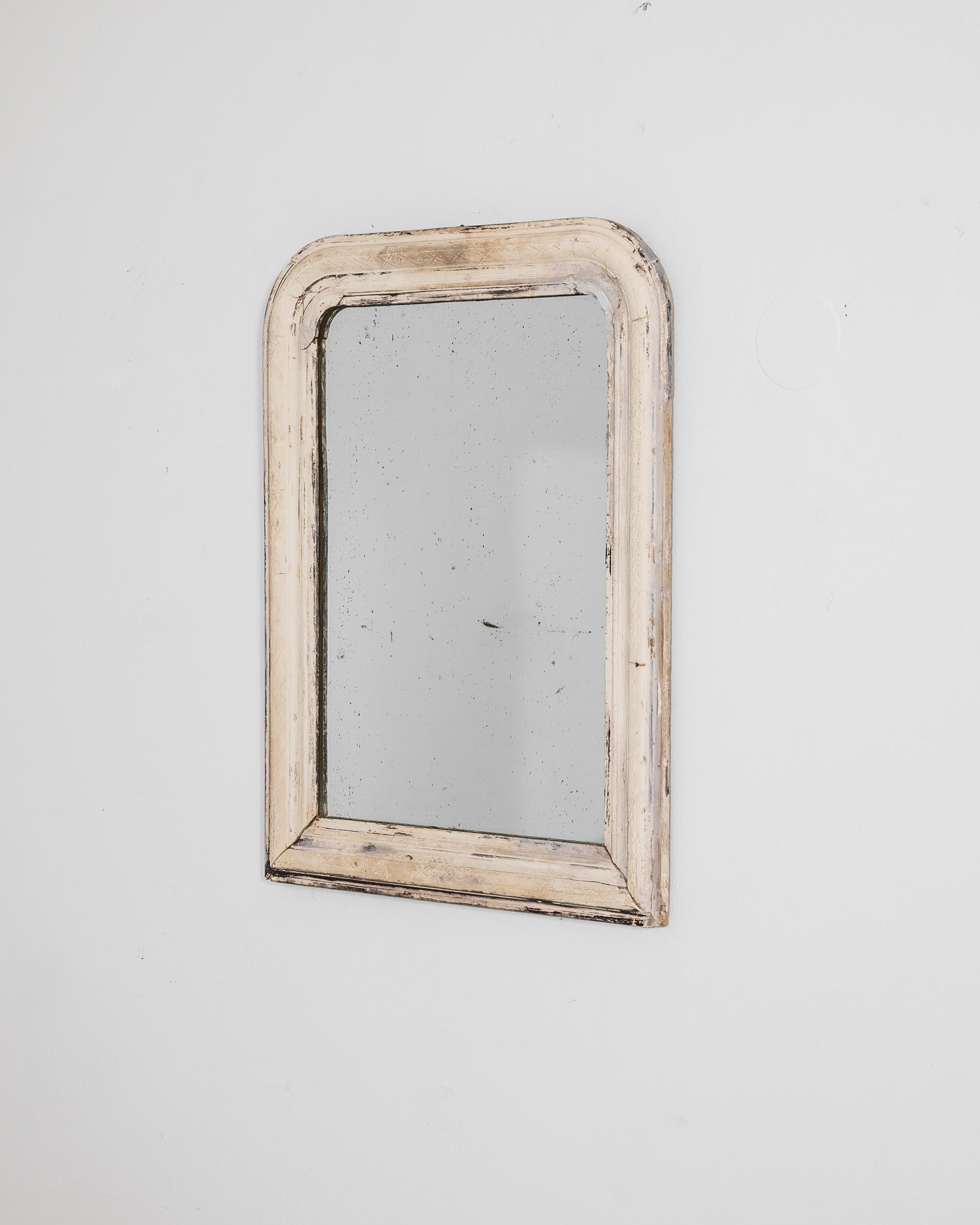 A timeworn piece with a youthful charm, this antique wooden mirror makes an enchanting addition to a bedroom or boudoir. Made in France circa 1880, rounded corners create a soft frame for the face; a delicate design of woven ribbons evoke the