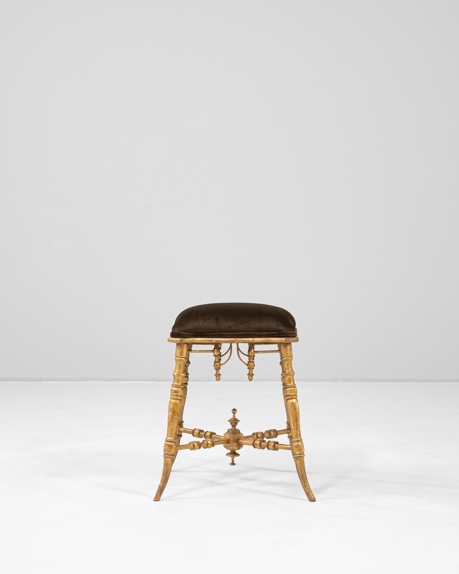 This 1880s French stool showcases exquisite craftsmanship with a turned and gilded wooden base, highlighted by intricate spindle detailing and finial accents. The rich gold patina enhances the sculptural quality of the legs, which curve gently
