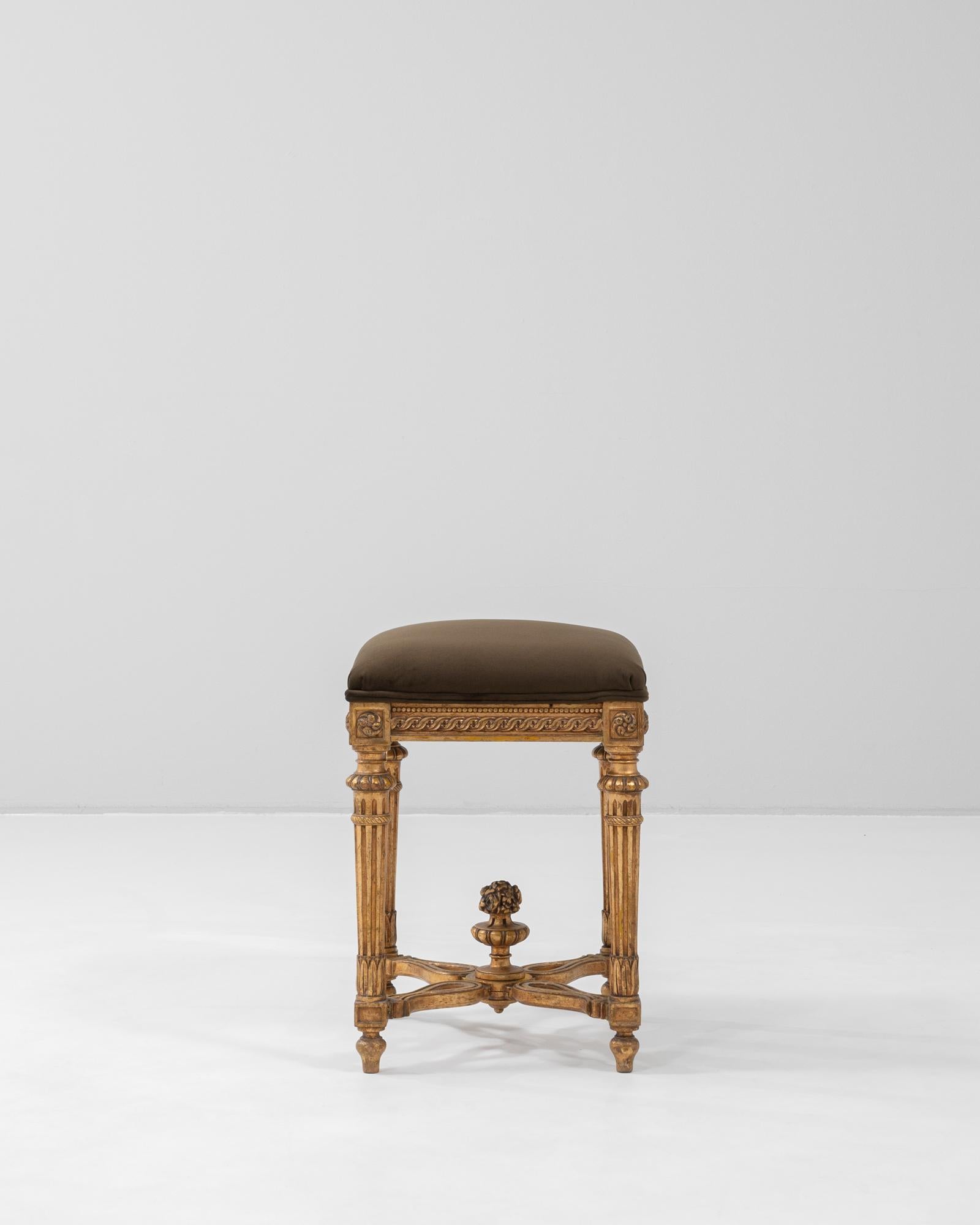Questo sgabello francese del 1880 è un raffinato esempio di stile Luigi XVI, caratterizzato da gambe scanalate, intagli a rosetta e proporzioni classiche. Realizzato in legno intagliato con una calda finitura dorata, lo sgabello presenta ornamenti