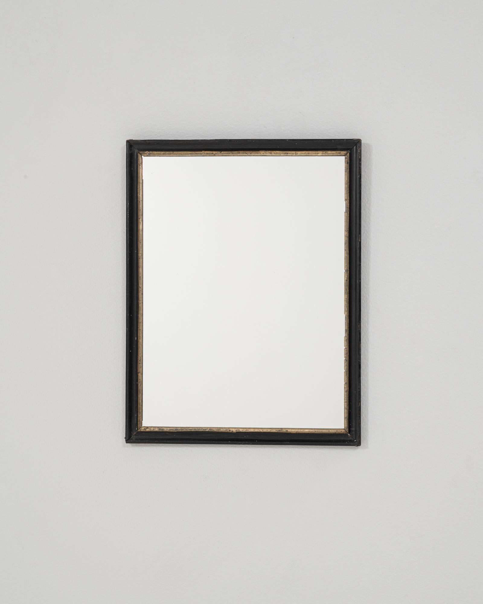 Ce miroir français des années 1880 est doté d'un cadre en bois simple et raffiné, recouvert d'une patine noire légèrement usée qui met en valeur son âge et son élégance discrète. Le profil linéaire est accentué par un fin bord intérieur doré,