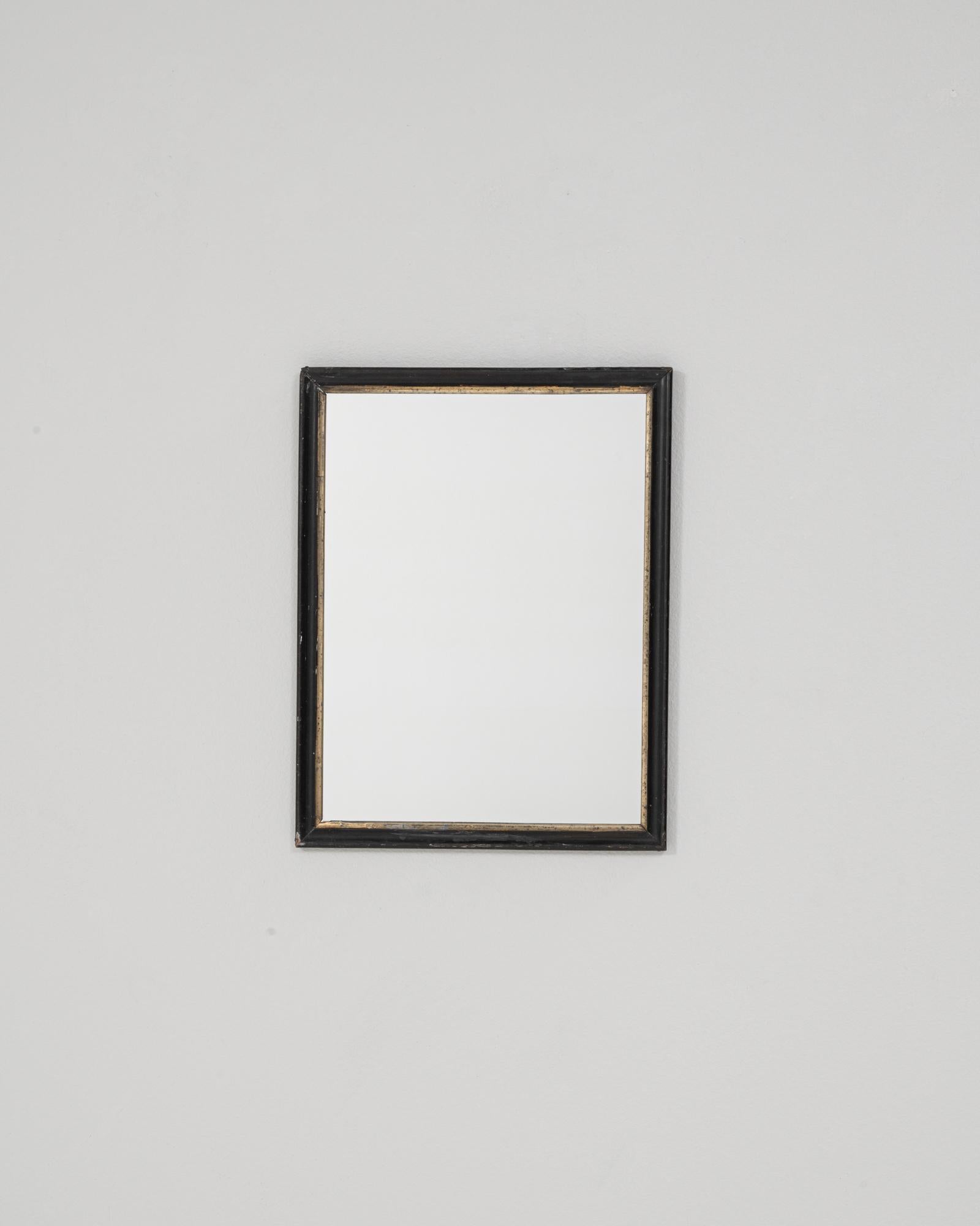 Ce miroir français des années 1880 est doté d'un cadre en bois simple et raffiné, recouvert d'une patine noire légèrement usée qui met en valeur son âge et son élégance discrète. Le profil linéaire est accentué par un fin bord intérieur doré,