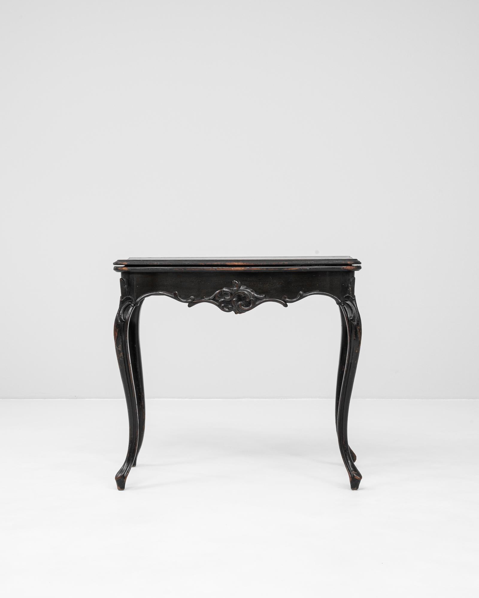 This 1880s French side table exemplifies the elegance of late 19th-century craftsmanship with its graceful cabriole legs and carved floral motifs. The solid wood frame is finished in a rich black patina, softly worn over time to reveal hints of the