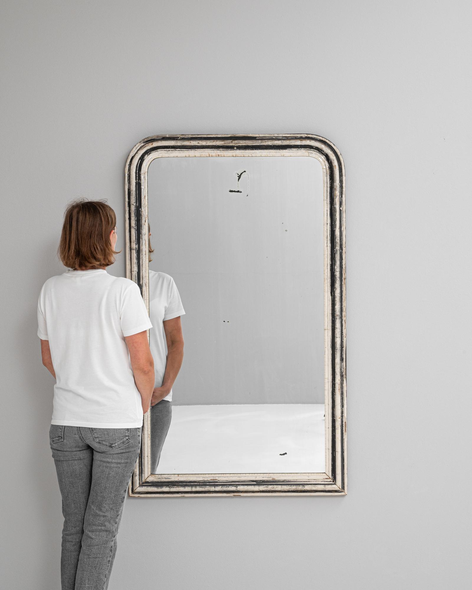 Ce miroir en bois français des années 1880 est un charmant mélange d'histoire et d'élégance. Il présente un cadre patiné caractéristique avec des couches de blanc et de noir qui ont naturellement vieilli avec le temps. Le sommet arrondi et les bords