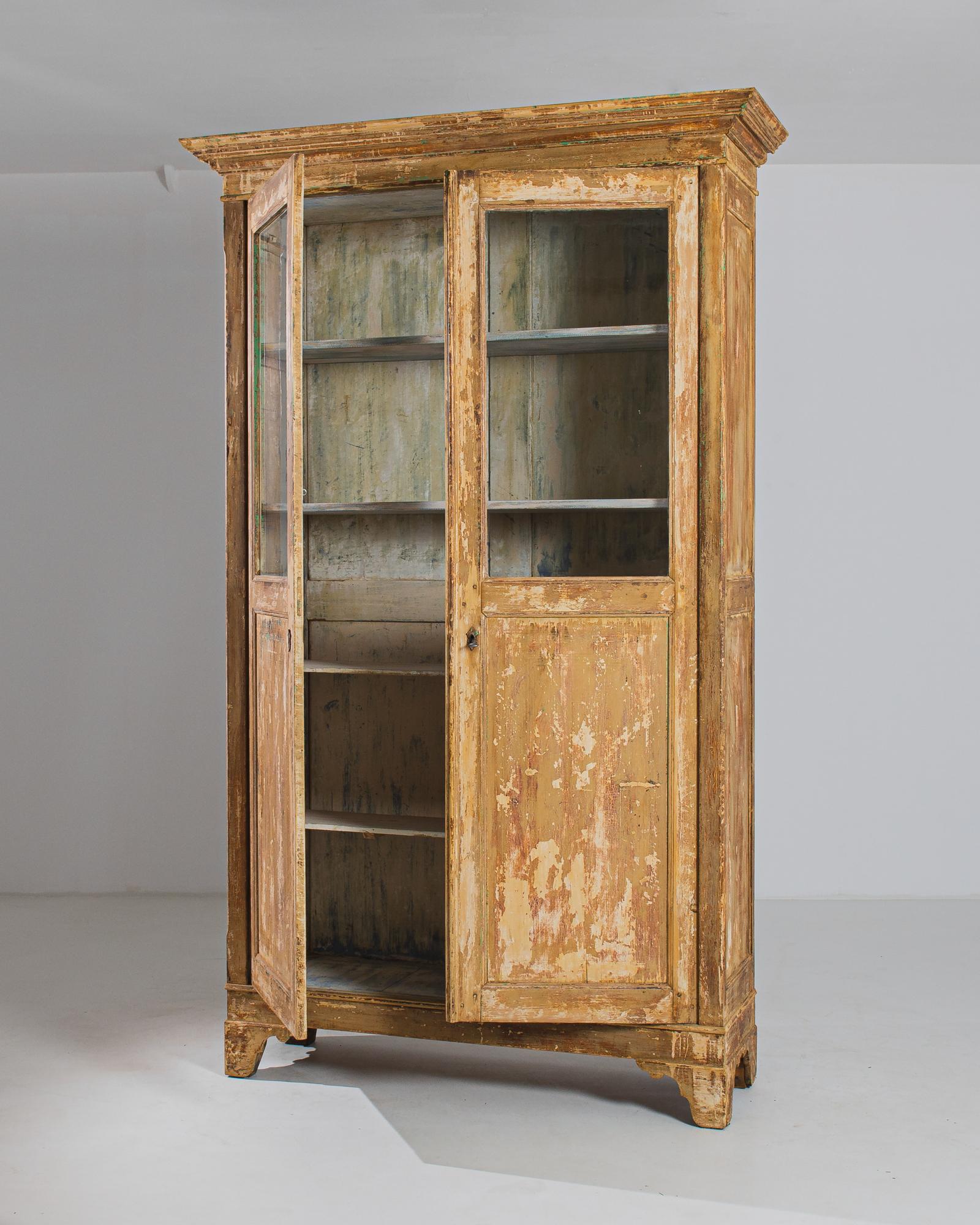 The 1880s French Wood Patinated Vitrine is a stunning piece that exudes timeless charm with its unique features. Adorned with a rich brown patina, the two doors open gracefully to reveal an enchanting interior. The top half of the doors is crafted