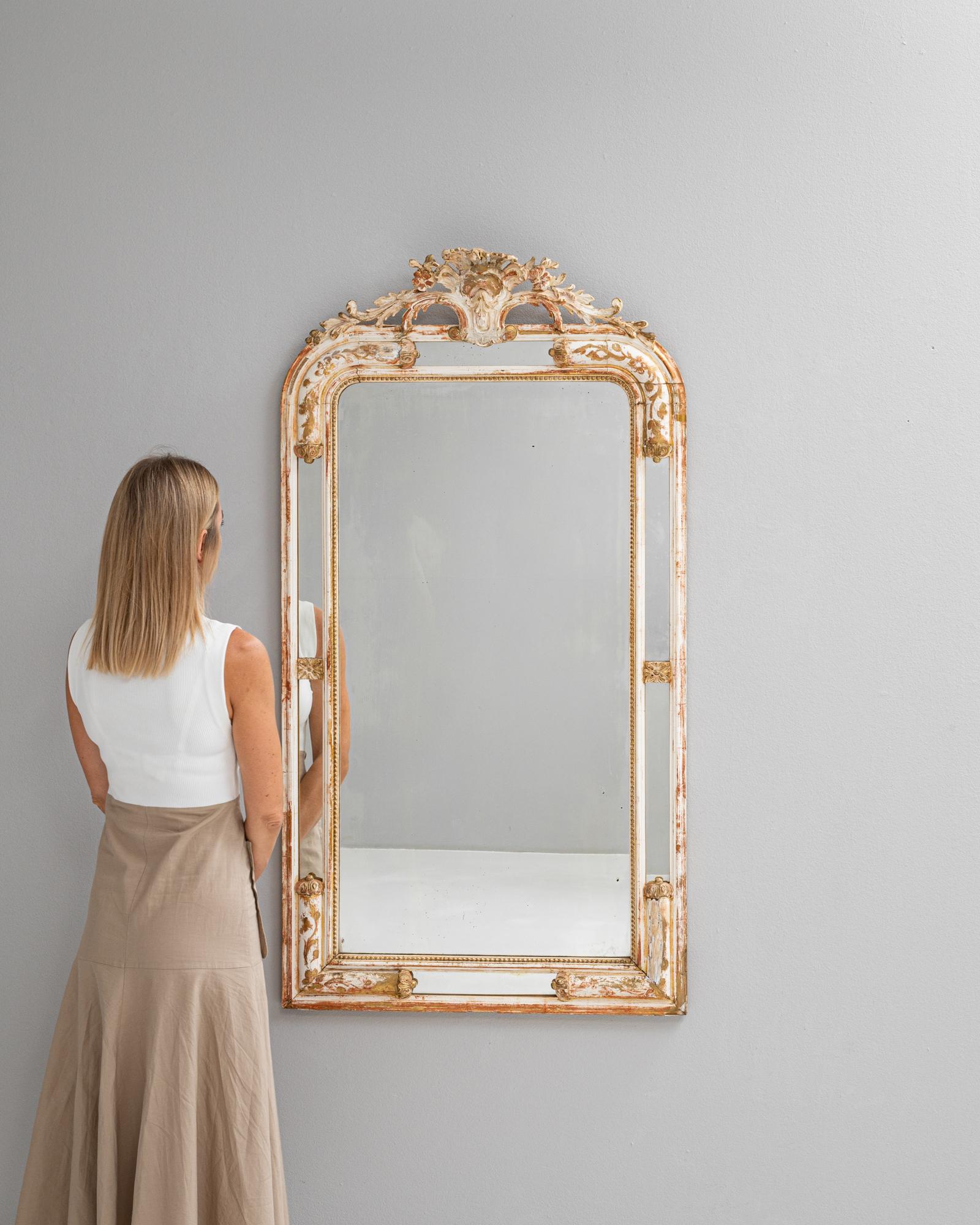Questo squisito specchio in legno francese del 1880 presenta una splendida finitura bianca patinata, che evoca un senso di raffinata eleganza e fascino antico. Gli intricati intagli che adornano la cornice dimostrano la maestria artigianale tipica