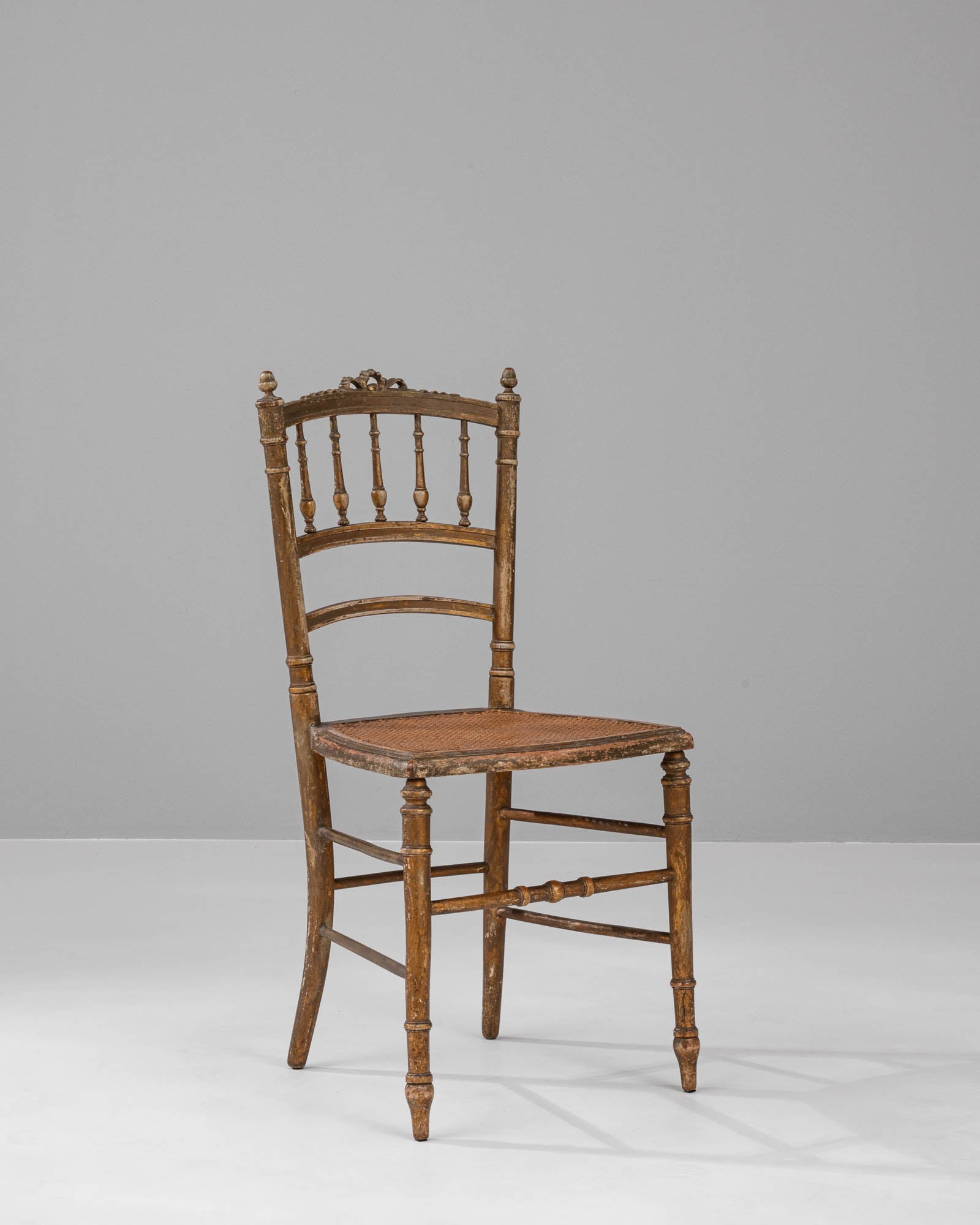 Step into a bygone era of elegance and charm with our authentic 1880s French Wooden Chair. This exquisite piece of history is crafted with meticulous attention to detail, evident in the turned spindle design and the gracefully arched ladder back