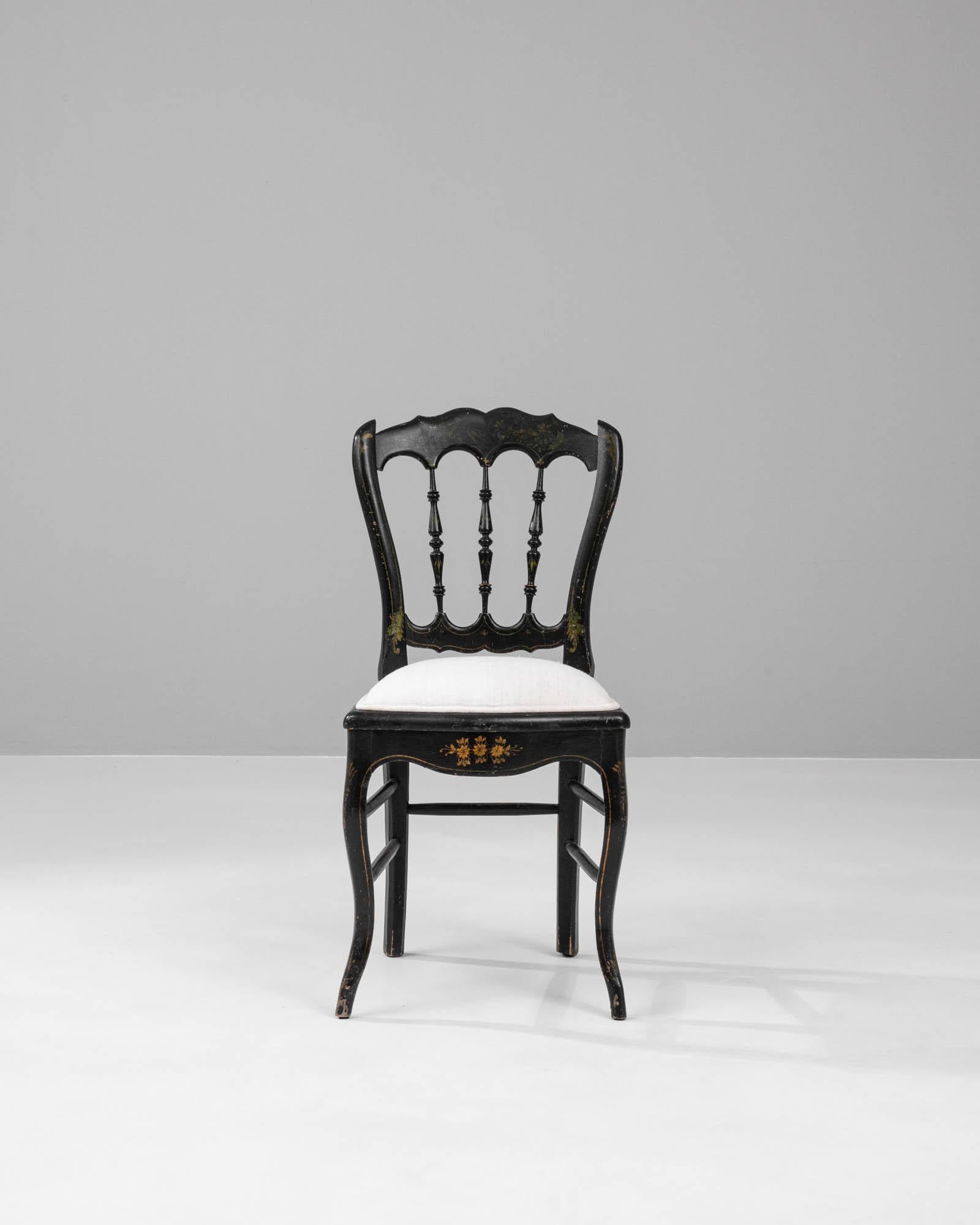 This 1880s French wooden chair with an upholstered seat is a beautiful example of the opulent design of the late 19th century. The chair's ebony-hued frame is gracefully adorned with golden floral motifs, their intricate details glistening against