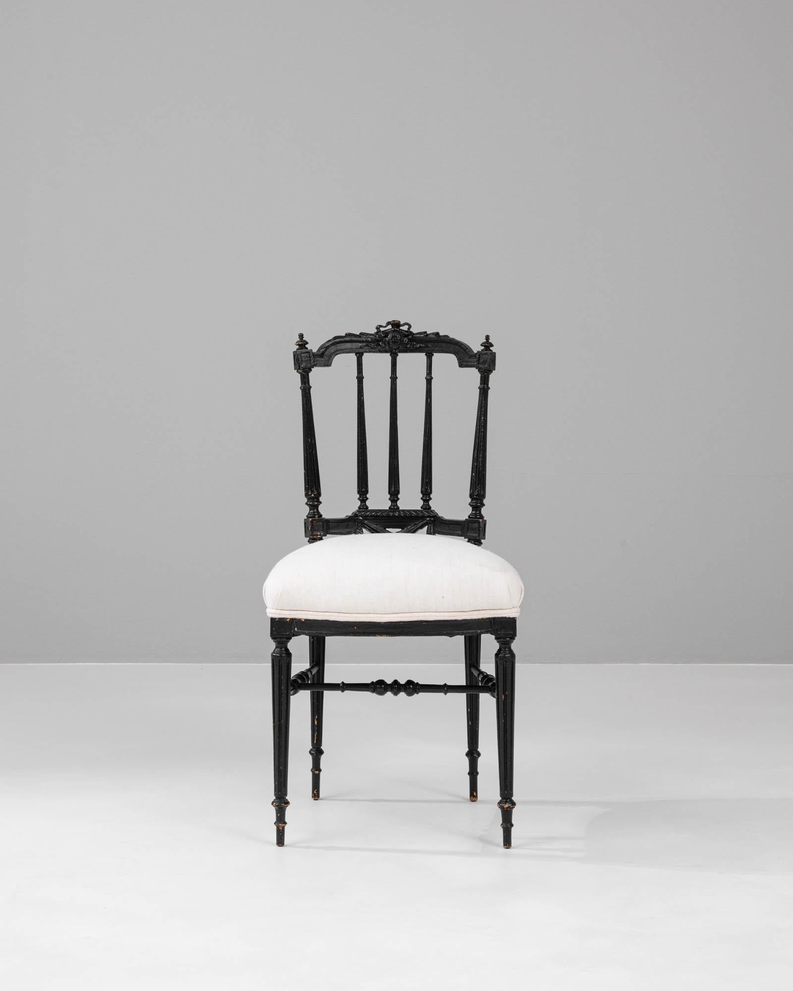 Emanating timeless elegance, this 1880s French wooden chair boasts an exquisite juxtaposition of the era's charm and a modern sensibility. The chair's high back is punctuated with slender spindles, capped with dainty finials that exude a gothic