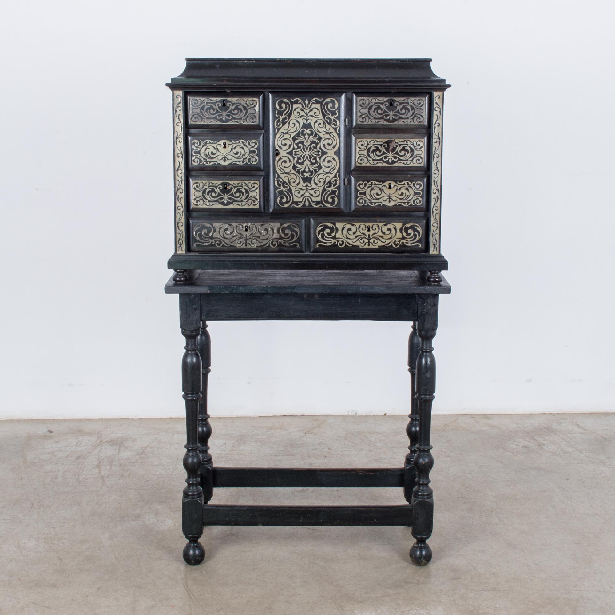 This impressive wooden chest of drawers was made in France, circa 1880, and is painted a glossy black with muted gold decorative scrolls on the face, with the original wood visible on the sides. The central compartment has a key and opens to reveal