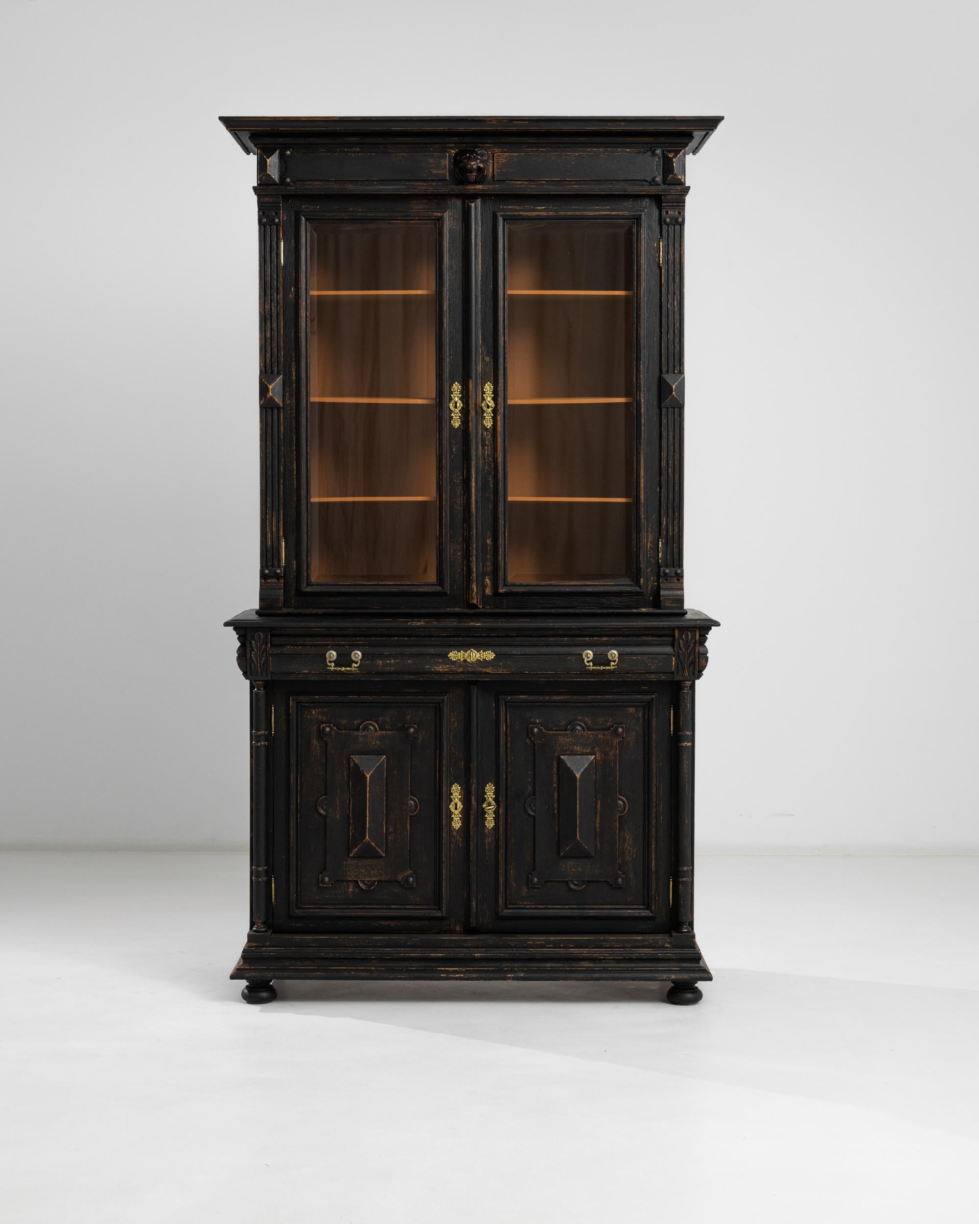 A wooden vitrine with original patina from France, produced circa 1880. A vibrant, antique vitrine constructed of black patinated wood standing at an impressive seven feet tall. Glass double door display peers into orange tinted interior of four