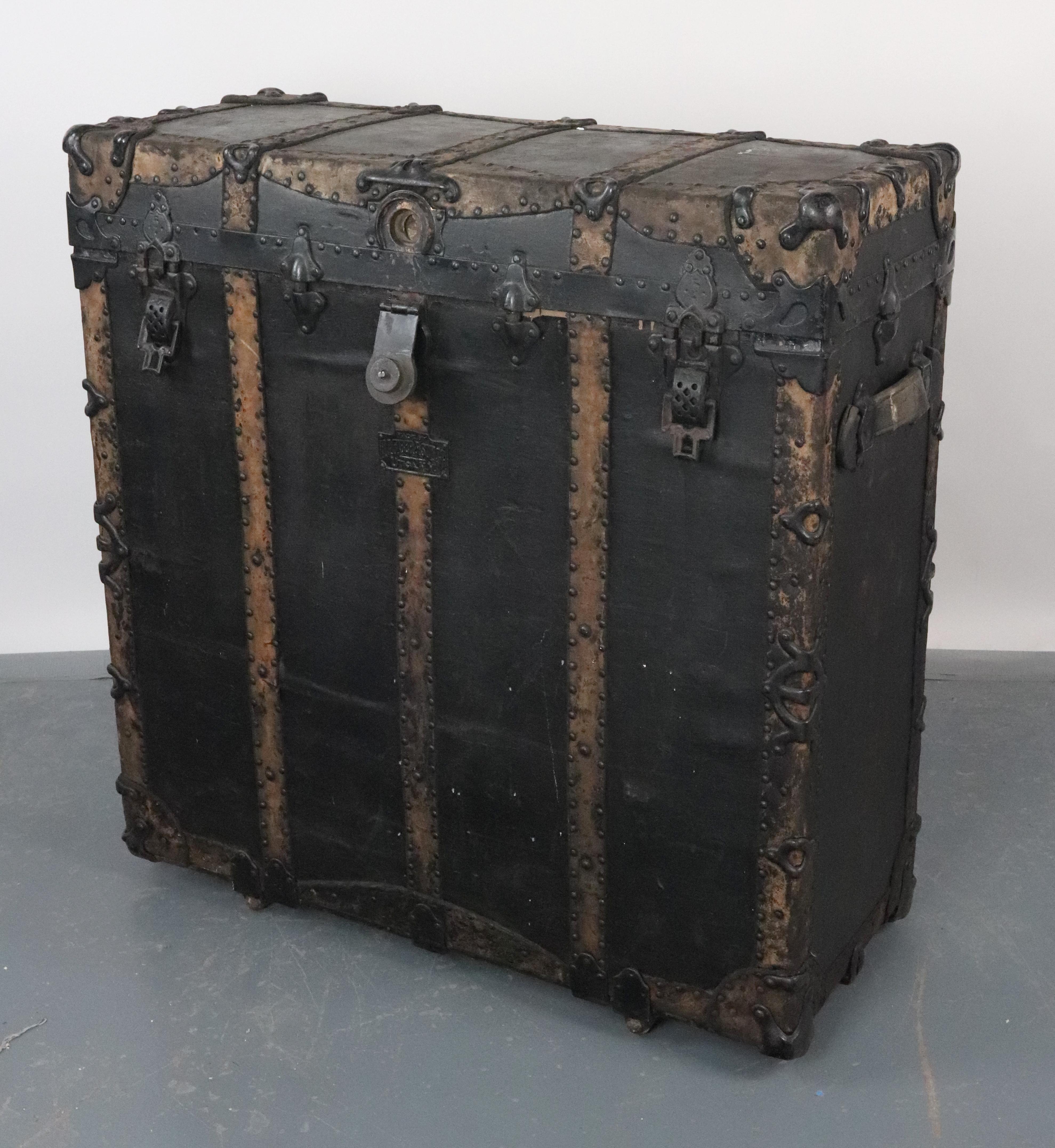Antico baule da viaggio in legno rilegato in pelle. La ferramenta è un mix di ghisa e acciaio con finitura nera. È stato prodotto da H. C. Faber & Son's Co., Utica, NY. La carta è strappata all'interno. L'esterno è in condizioni originali. Buone