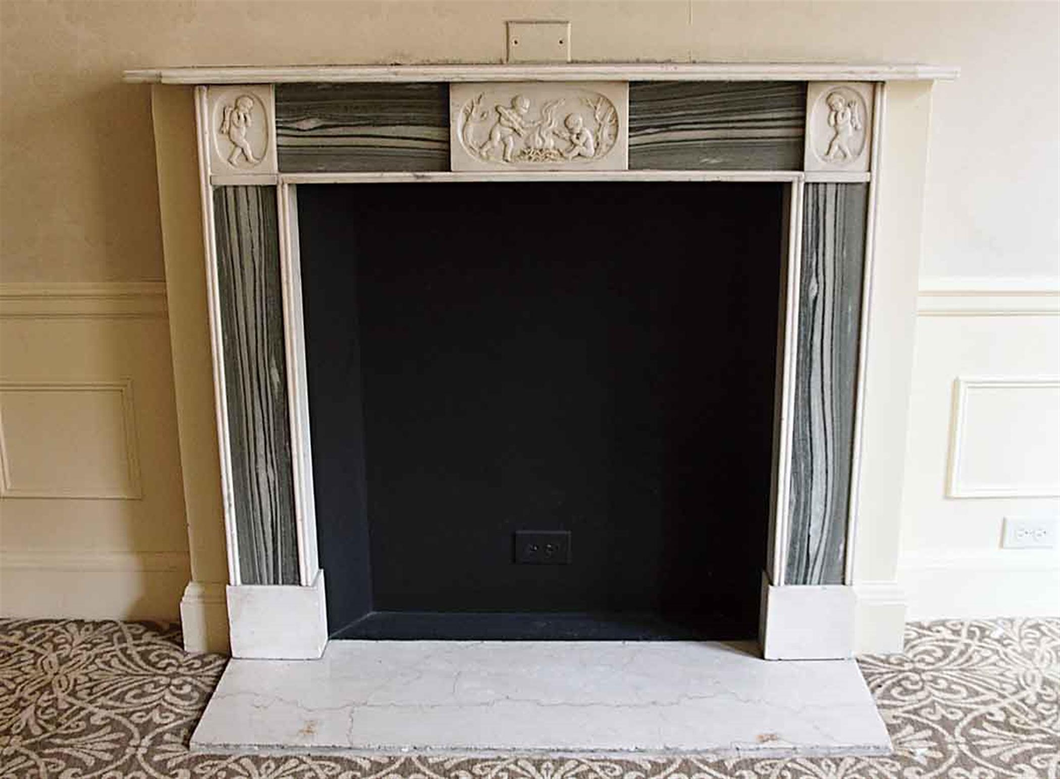 English Regency green and white marble mantel with cherubic motifs. This mantel was one of a group of antique mantels imported from Europe and installed in the NYC Waldorf Astoria Hotel in 1931 when the hotel was first built on Park Avenue. This