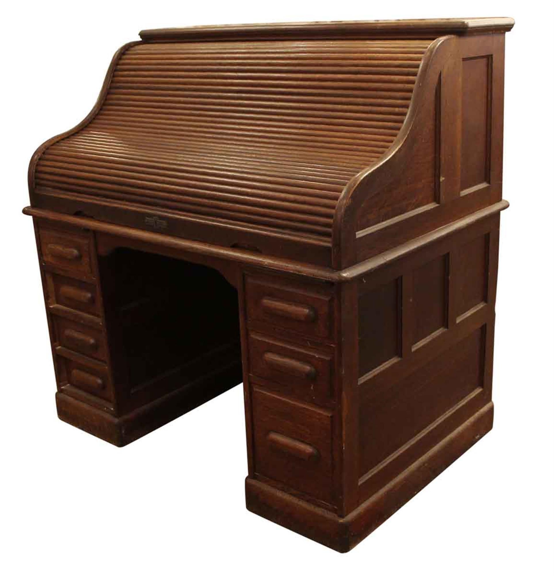 Seven drawer dark wood tone roll top desk with extra inside storage and cubbyholes from the 1880s. This can be seen at our 2420 Broadway location in the upper west side in Manhattan.