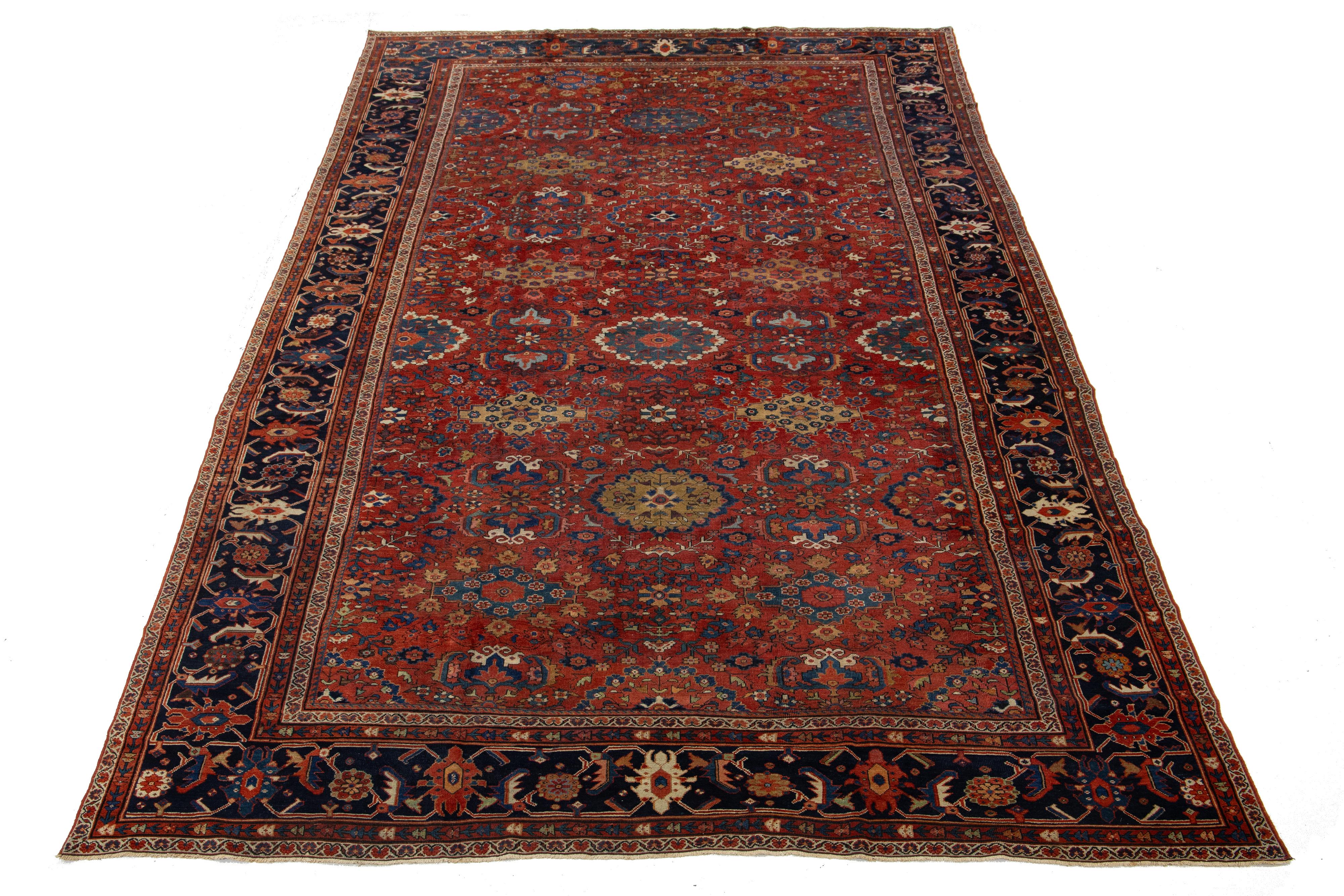 Ce tapis ancien en laine de Sultanabad, datant des années 1880, présente un champ rouge-rouille orné d'accents multicolores dans un motif floral typique des tapis persans. La durabilité du tapis est soulignée par son tissage en laine robuste, obtenu
