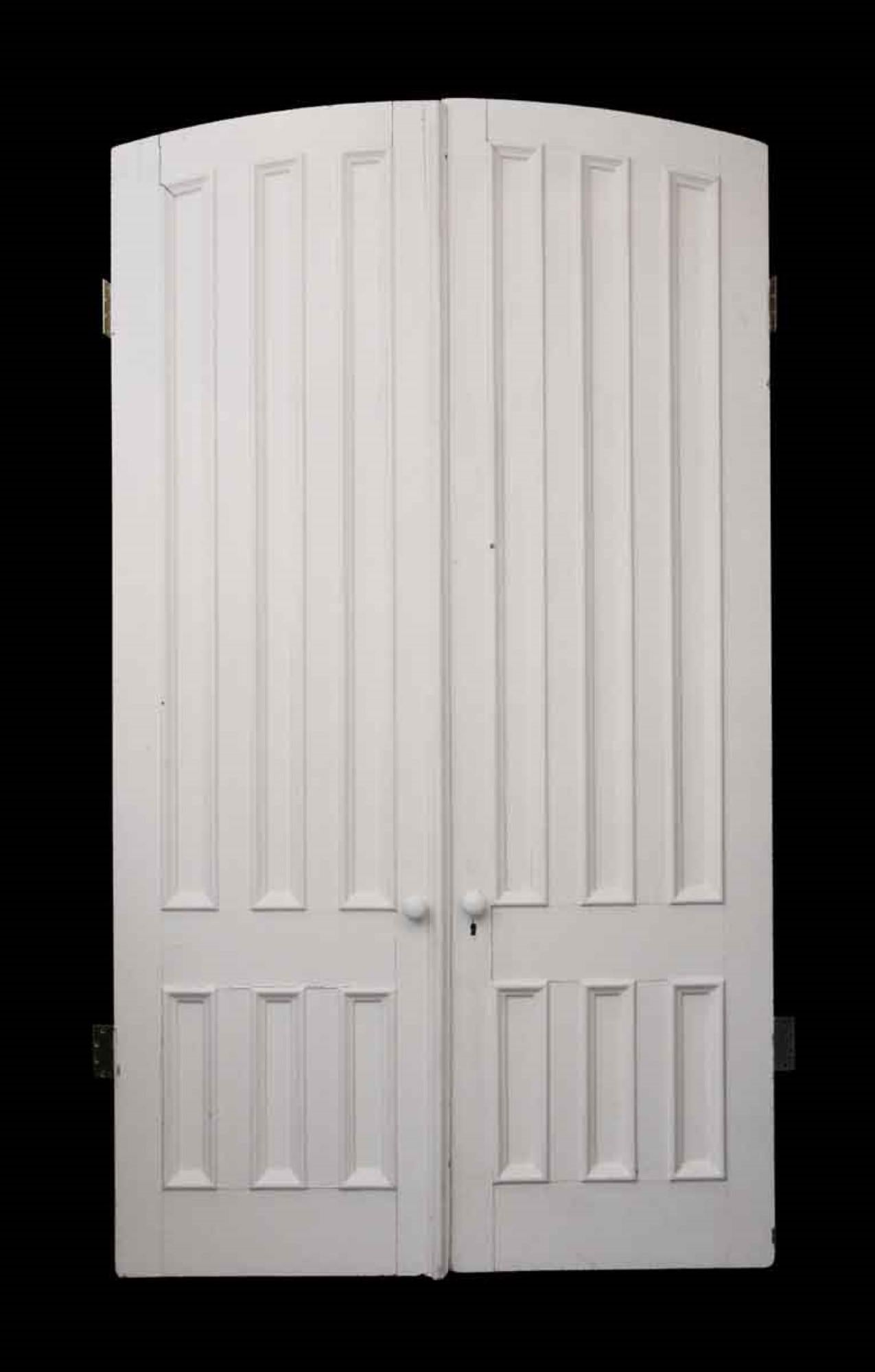 Very thick pair of interior parlor doors painted white. Features the original porcelain door handles from the 1880s. Each door has six narrow recessed panels with raised side moldings. Gentle arch on top. Measures: 107 x 60.5. This can be seen at