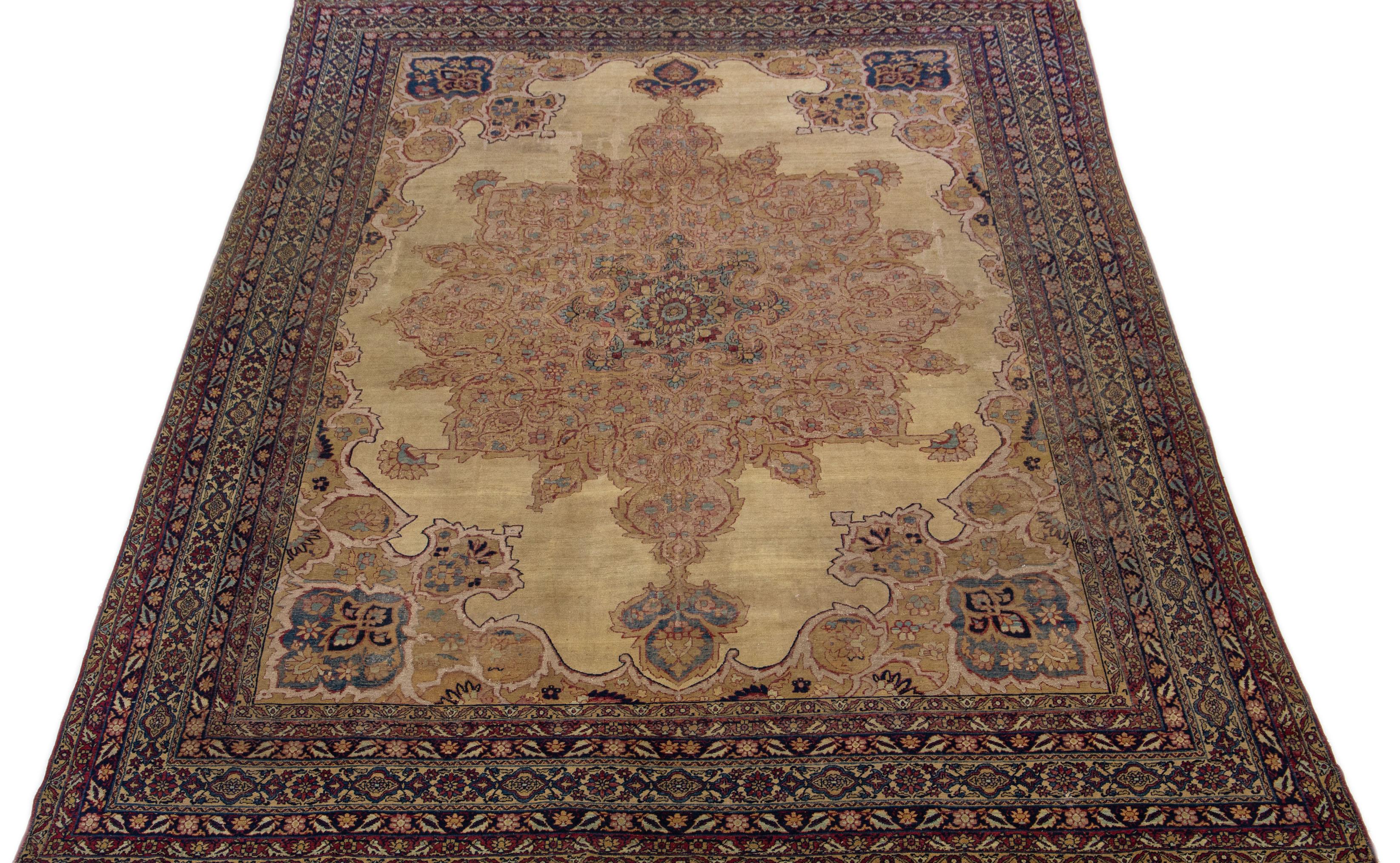 This stunning Kerman wool rug has been hand-knotted with antique craftsmanship. Its color field is a lovely tan. It is complemented by an intricately designed frame and accented by multicolors in a gorgeous all-over floral medallion motif of Persian