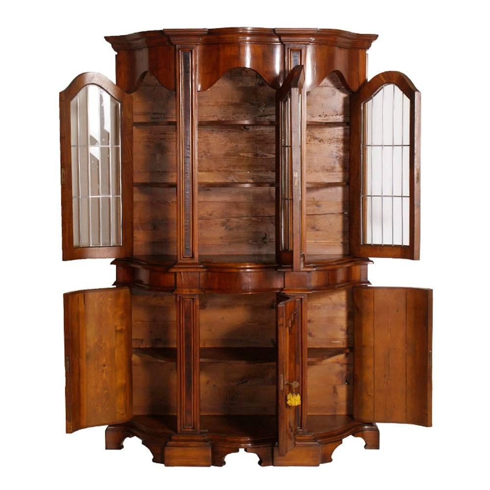 Aparador con vitrina, estilo Renacimiento Barroco, del pasado siglo XIX, en nogal macizo, carpeta de nogal burl y carpeta de nogal. Parte superior de tres puertas con cristal emplomado y dos estantes interiores. Parte inferior en tres puertas con