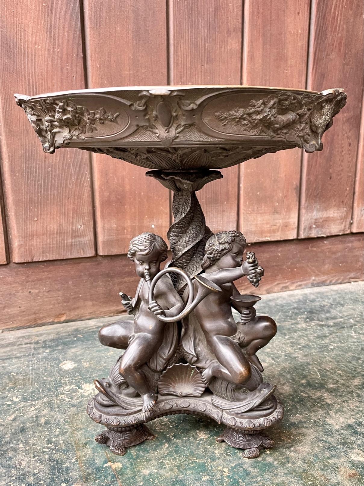 An unpolished patinated French 19th century cast bronze Tazza bowl supported by three seated cherubs in fine details, on a tripod of sea creatures; fish and turtles. Very heavy. Procured from a fine Washington DC Estate. No makers markings found on