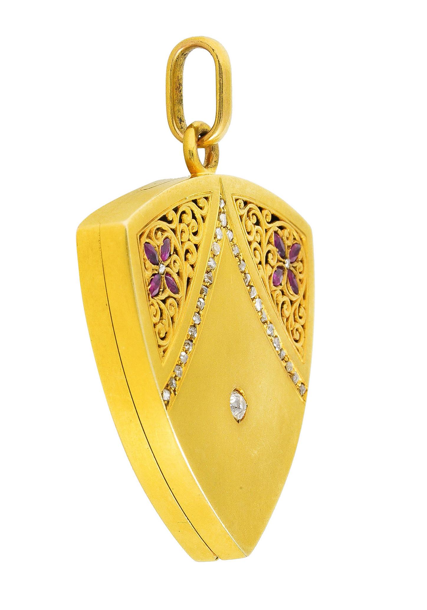 Pendant is shield in form and pierced with decoratively scrolling foliate. With floral motifs comprised of marquise cut rubies. Weighing in total approximately 0.30 carat - purplish red in color. Centering an old mine cut diamond weighing