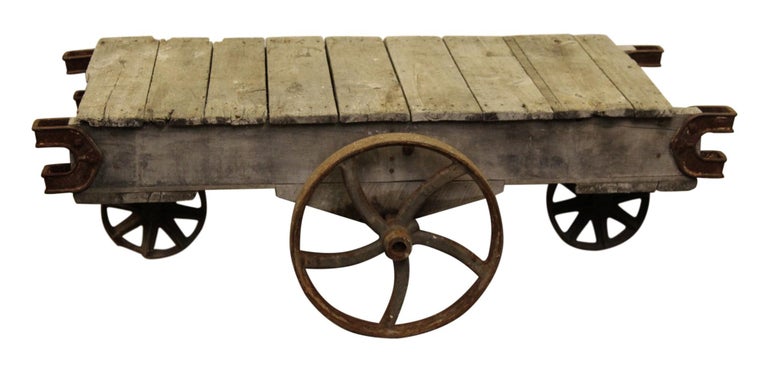 Made in the late 1800's, this wood factory cart has a rustic look featuring wood slabs and cast iron wheels. The natural rust and wear with age adds to its authenticity along with it's original patina. There are many possibilities now for it such as