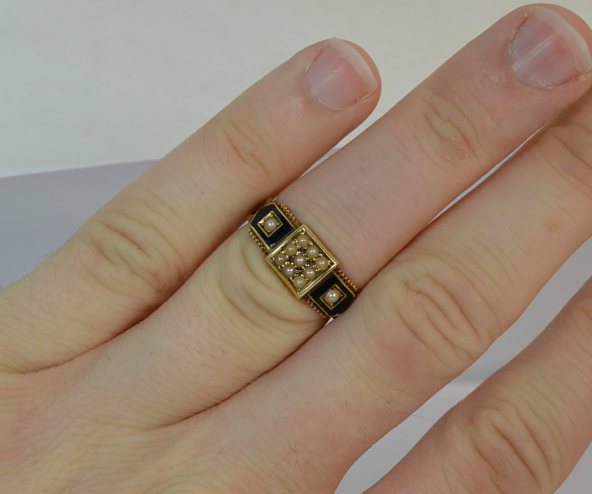 
A rare Victorian period mourning ring.

Solid 15 carat yellow gold example.

​Designed with a 3x3 grid of seed pearls to the square head front with a further pearl to each side in black enamel. The shank is finely hand engraved with braided hair