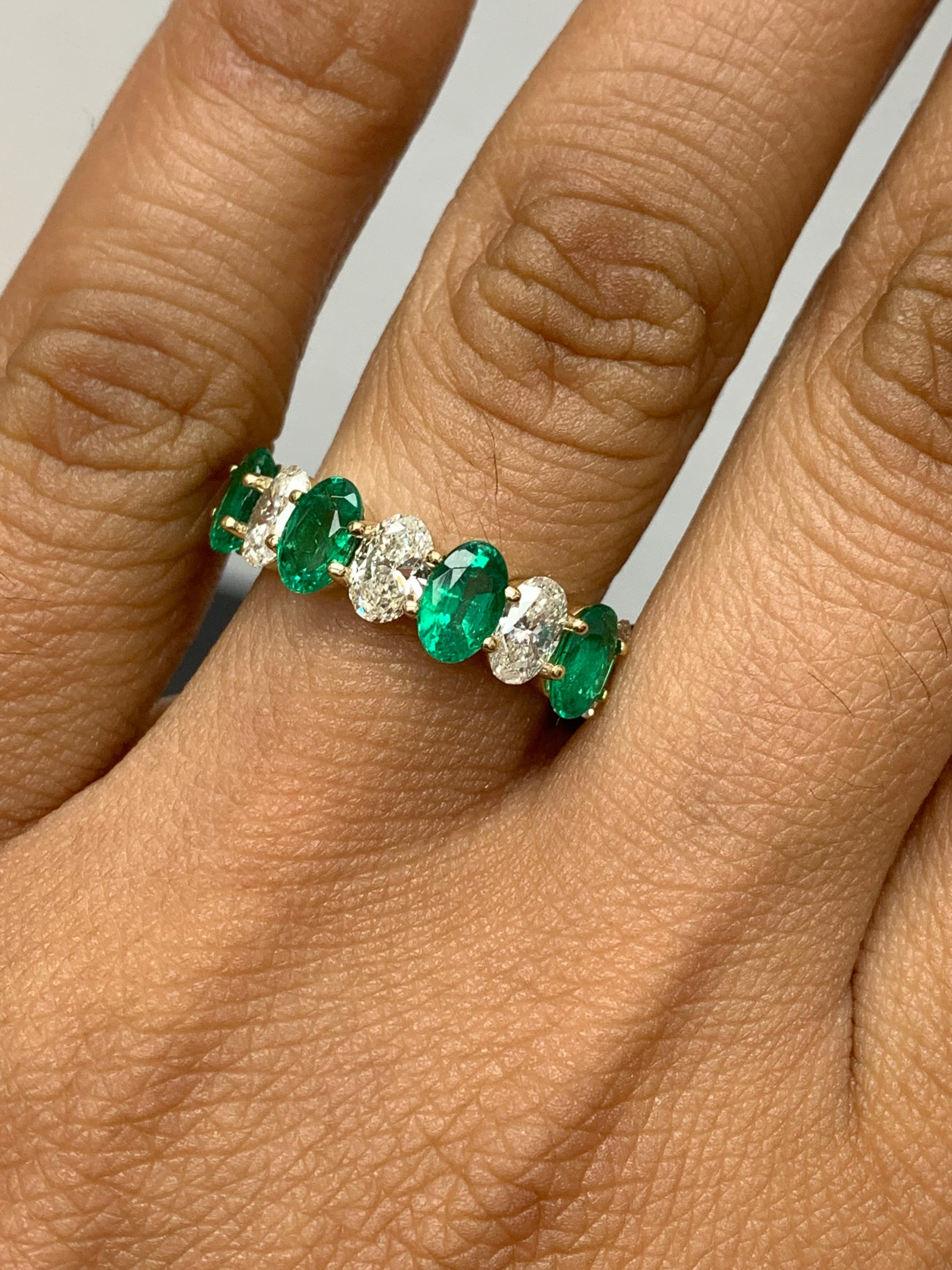 A fascinating gemstone wedding band 9 stone style showcasing lush green 5 oval cut emeralds weighing 1.89 carats total, alternating to these emeralds are 4 oval cut brilliant colorless diamonds weighing 1.26 carats, Made in 14K Yellow Gold, Size 6.5