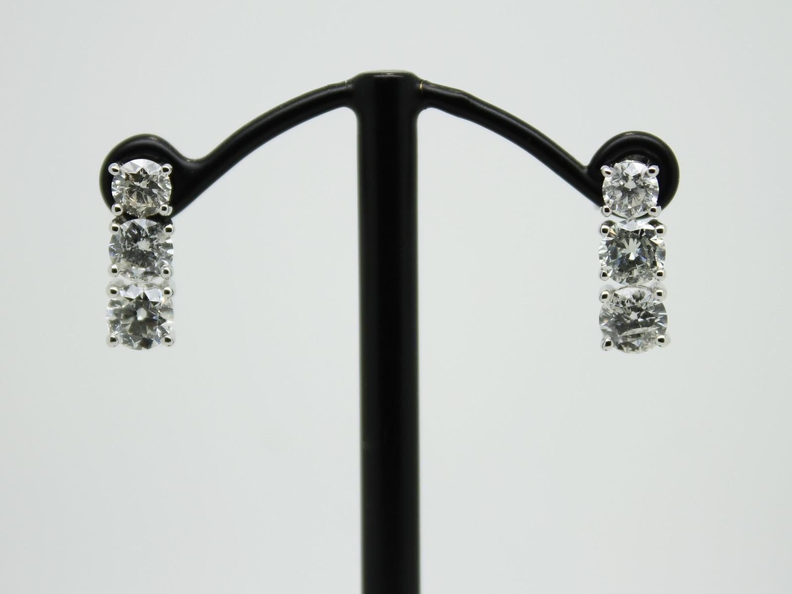 A beautiful Pair of graduated round brilliant cut three-stone diamond drop earrings in, featuring a total of 1.89 carat diamond colour H/I clarity SI / I, each stone is set in a classic 4 claw mount with post and butterfly fittings, in 18 karat