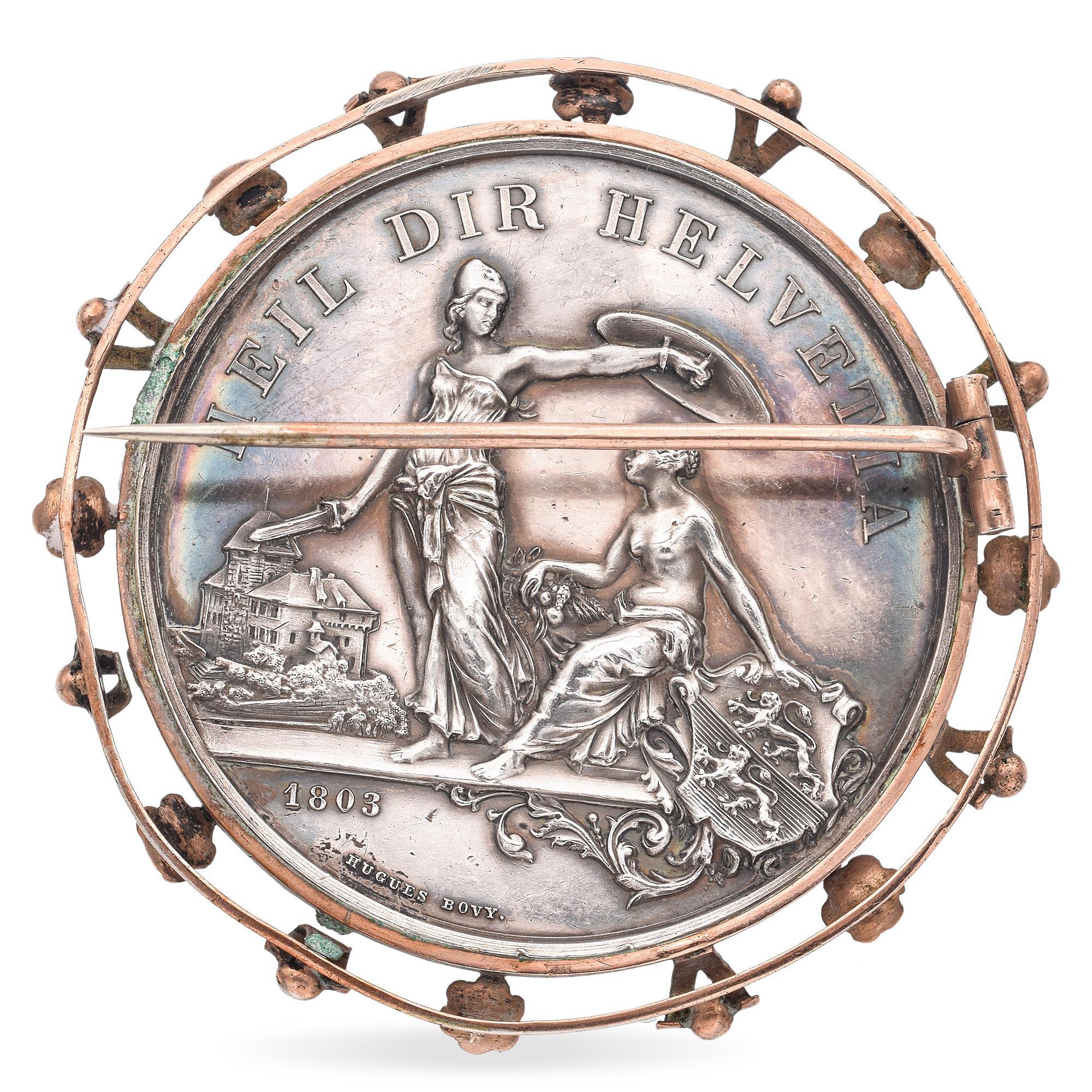 Questa intricata spilla d'argento affascina per la sua lavorazione dettagliata e per il significato storico della tradizionale gara di tiro della Svizzera.
Realizzato in Svizzera nel luglio del 1890, presenta un medaglione centrale ornato da uno