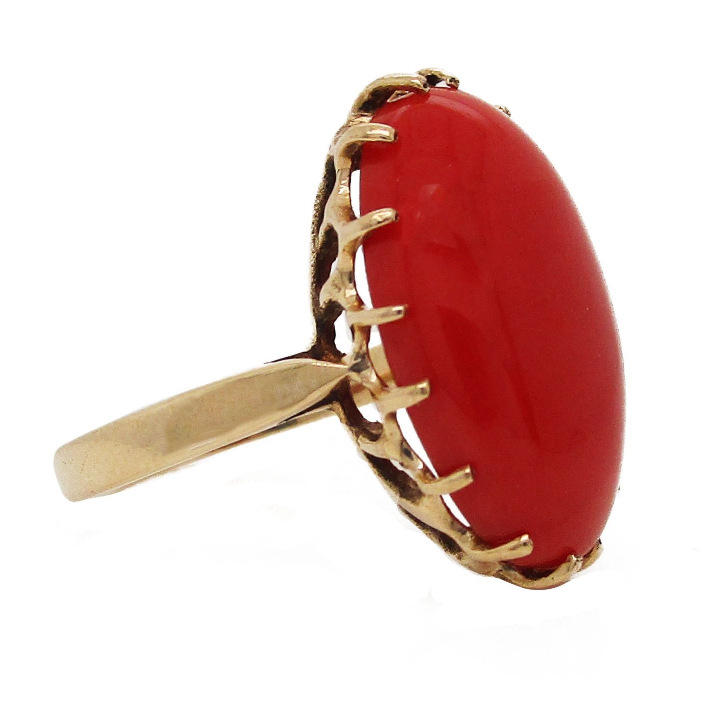 This 1890 Victorian ring pairs bright 14k yellow gold with a red coral cabochon whose natural color will take your breath away! The 14k yellow gold ring stretches into a two-layered pierced undergallery. The open layout of the ring exposes the back