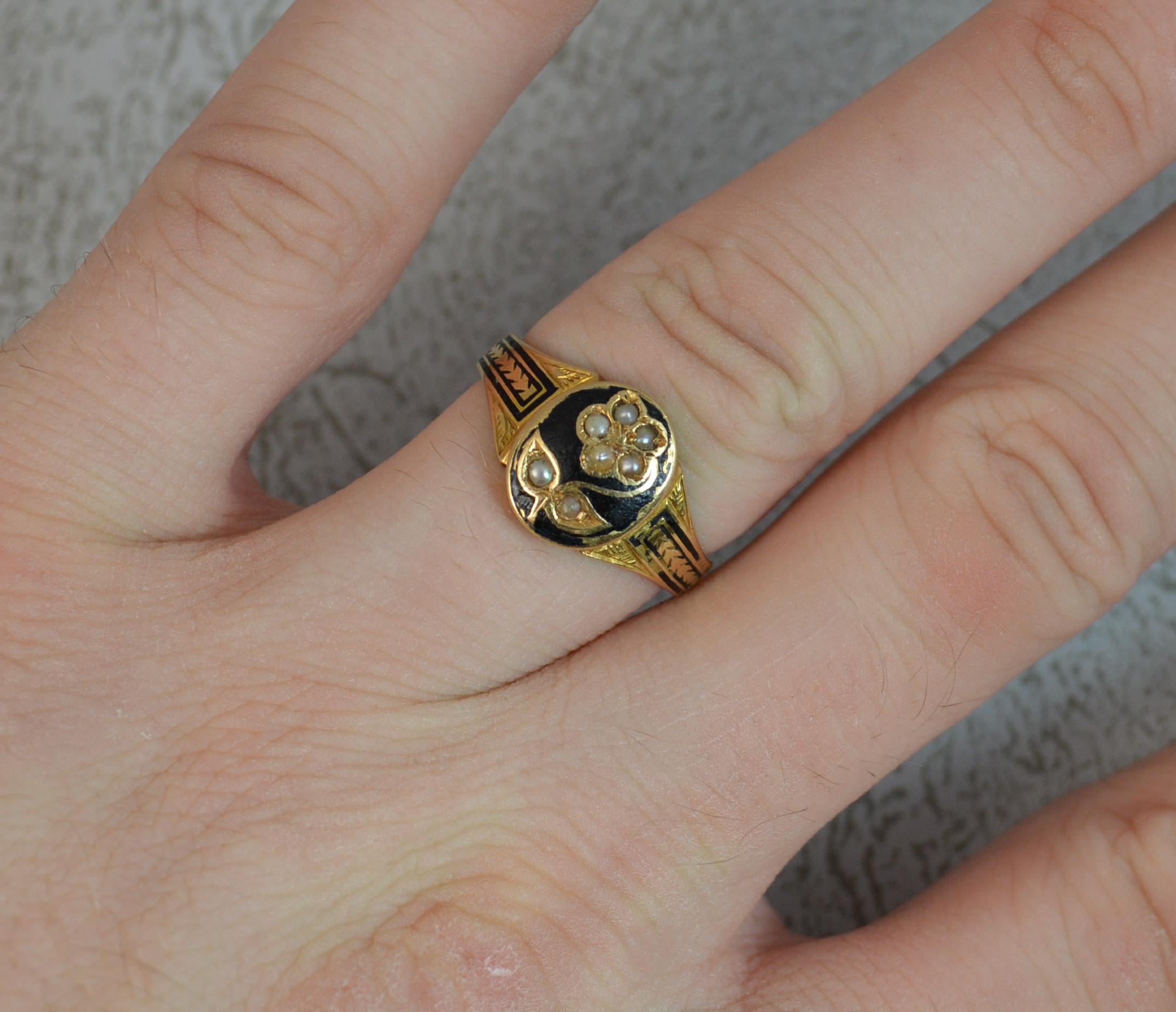 A Victorian period mourning ring. 18 carat gold example. Designed with an oval head with flower design in gold set with seed pearls and black enamel surrounding. Further enamel is to each shoulder.
Size O UK, 7 US.
The outside of the band to read;