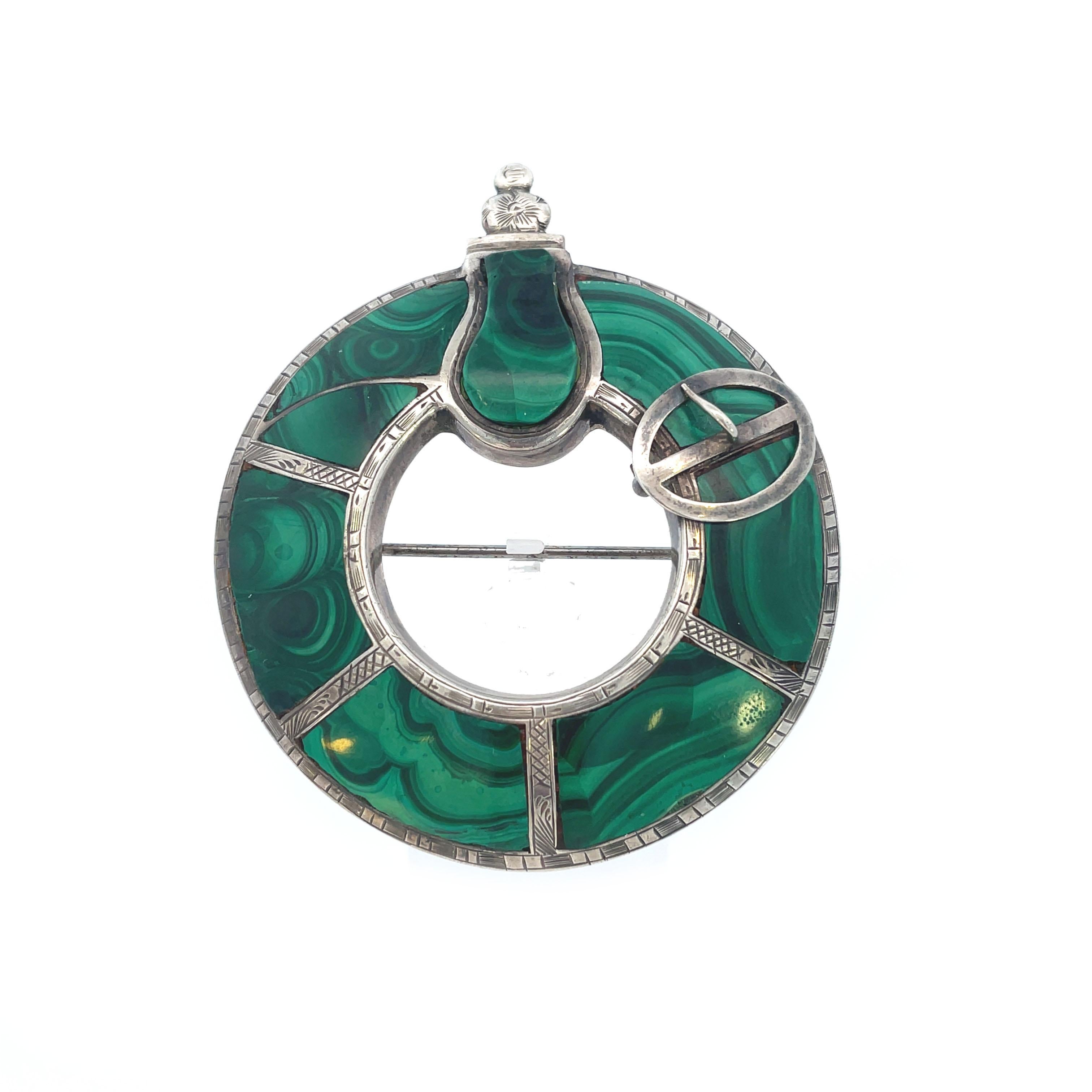 This is a super unique Victorian pin crafted in sterling silver that features vibrant green Malachite. Bordered in bright sterling silver, shaped Malachite encircles the entirety of this striking pin. Marbled and rich green Malachite split between