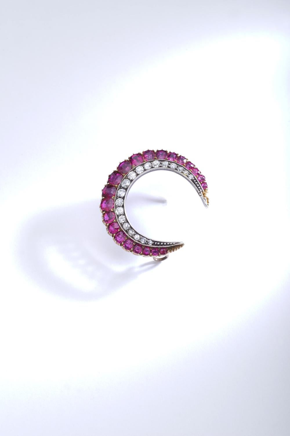 Crescent Ruby Diamond Brooch. 
Silver and pink gold.
Crescent brooch, set with cushion-shaped and round rubies.
Circa 1890.

Diameter approximately 1.18 inch.