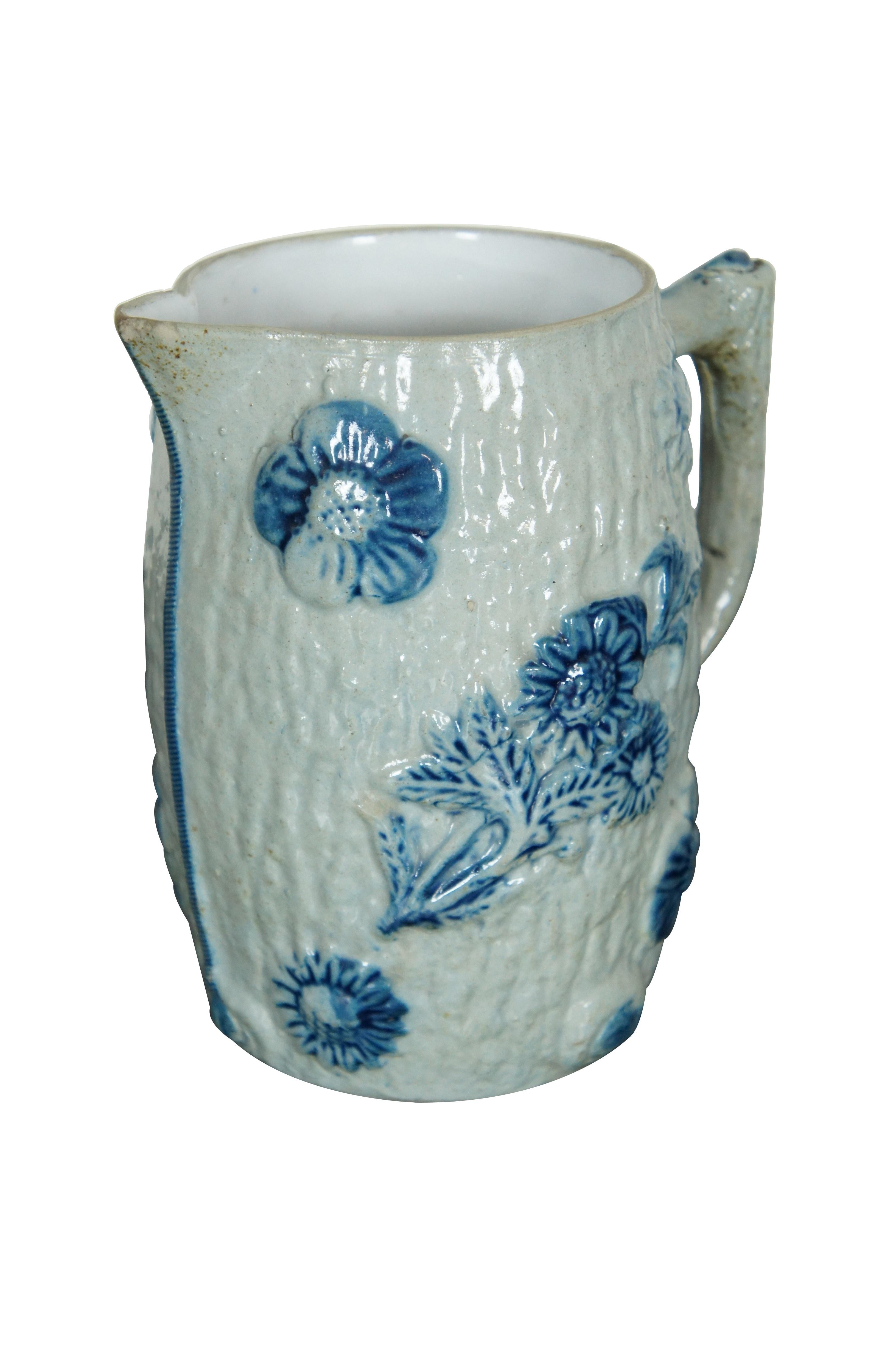 Flemish Whites of Utica, New York, circa 1890s salt glaze stoneware pitcher.  Features a white tree bark design with raised blue sunflowers and what a appears to be pine branches.

Whites of Utica
Utica, New York State. United States.

Hersteller /